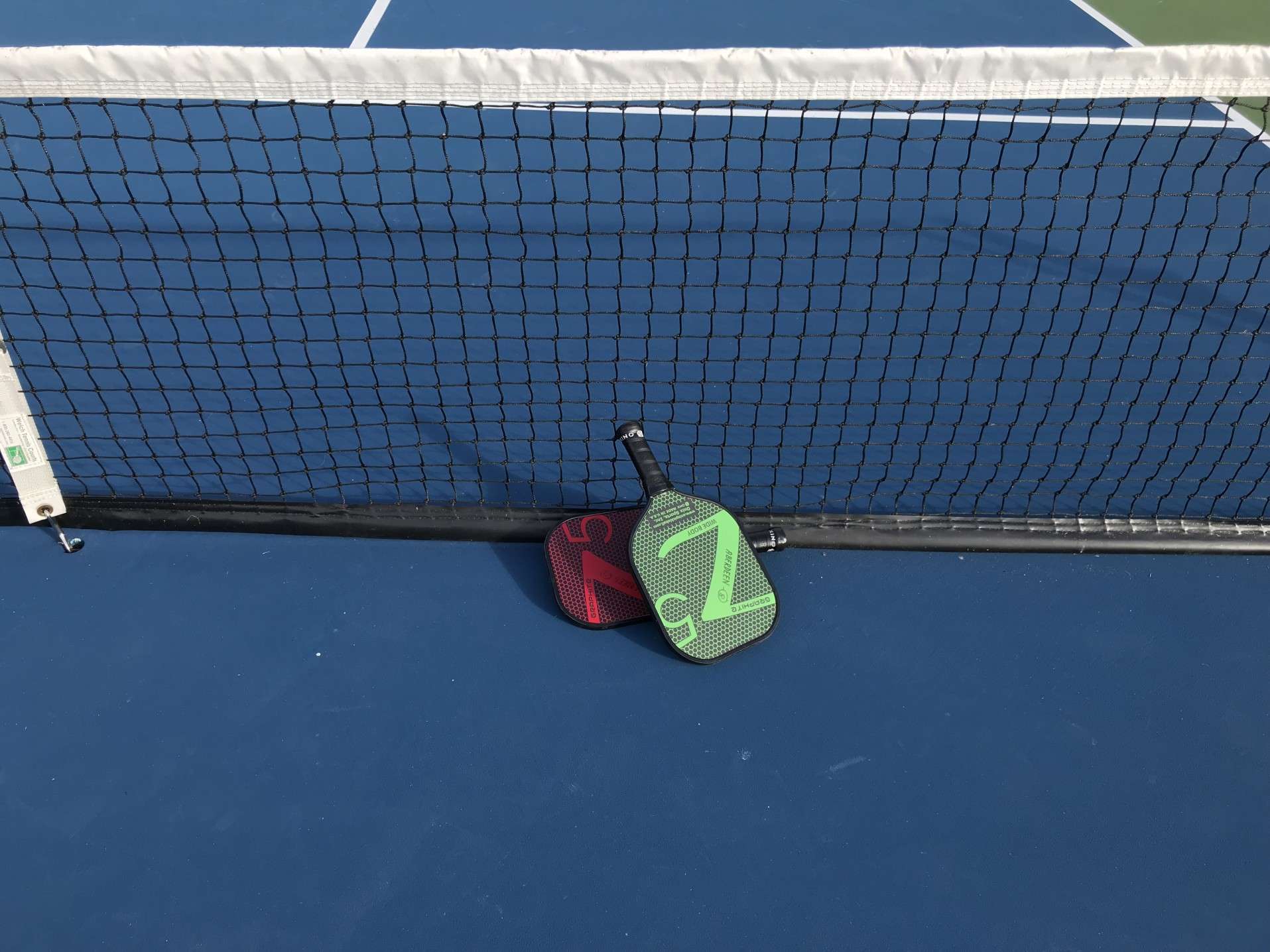 Two pickleball paddles sitting next to net