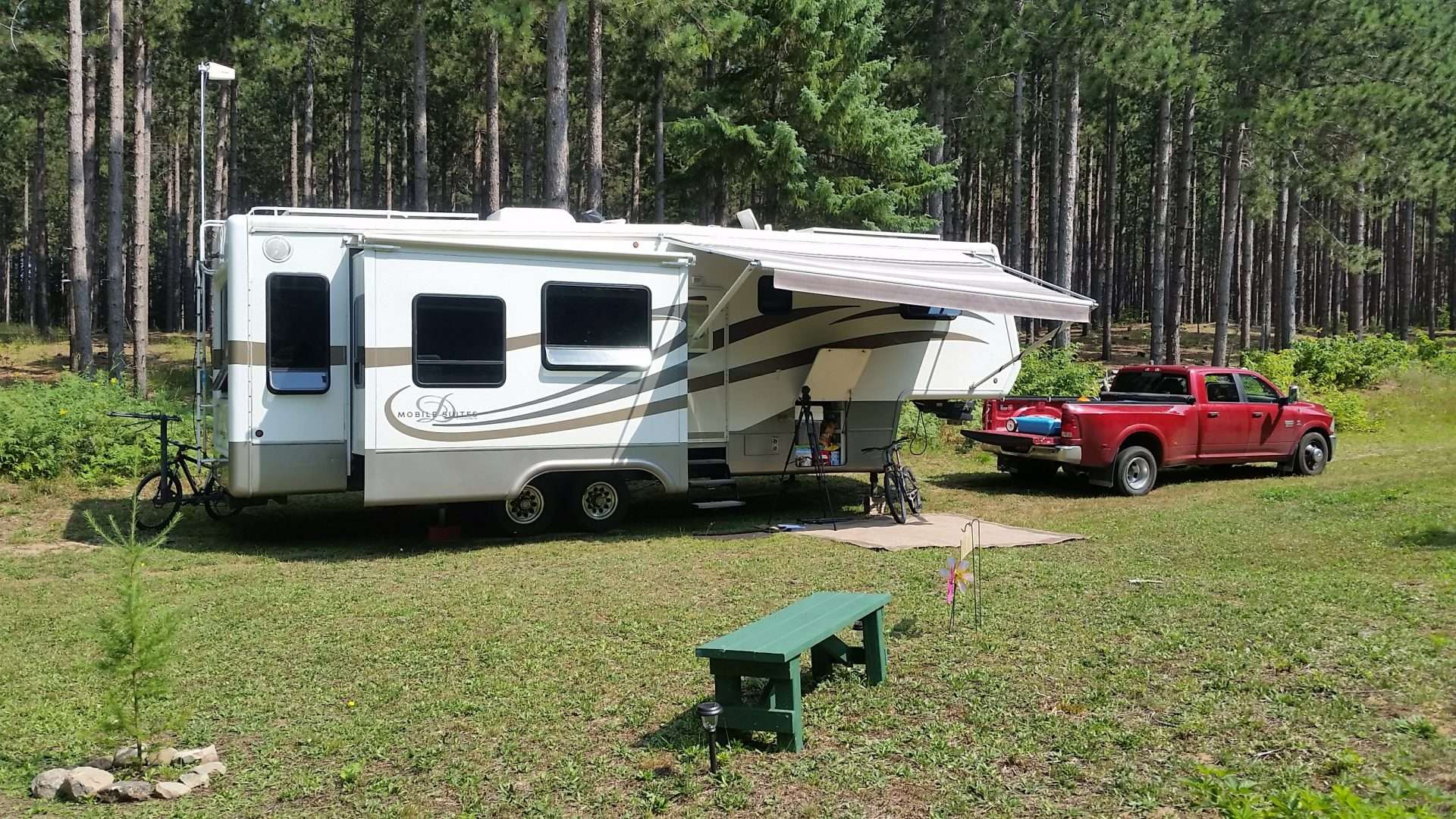 Mortons on the Move fifth wheel RV parked at campsite in forest.
