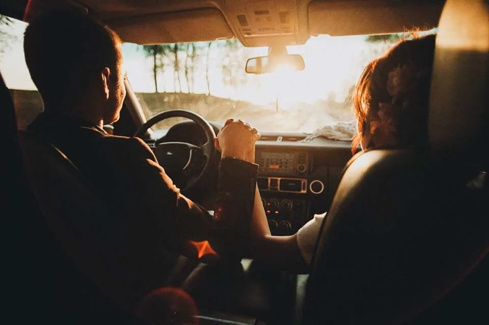 Couple holding hands while driving into the sunset