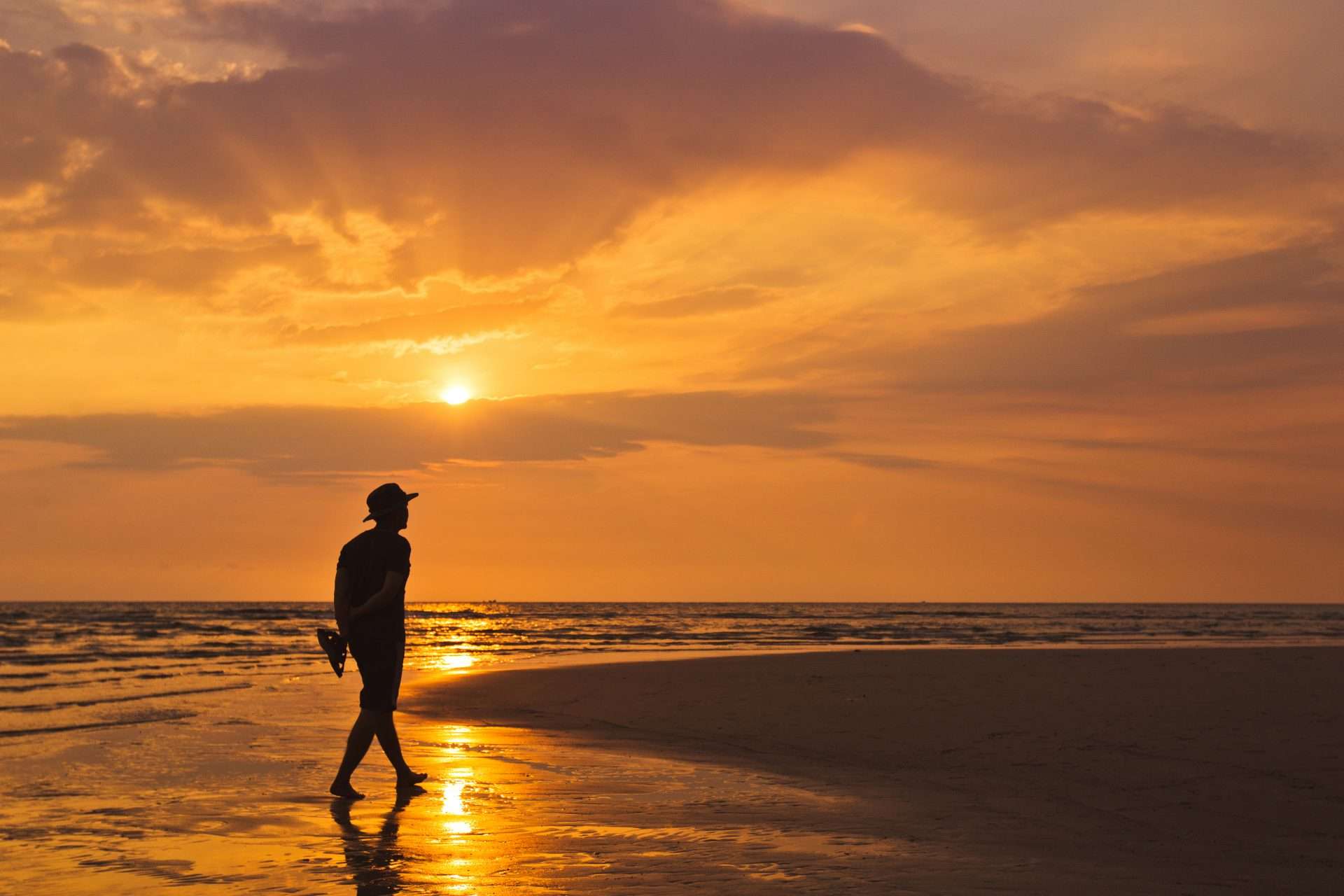 Man walking along the beach at sunset 