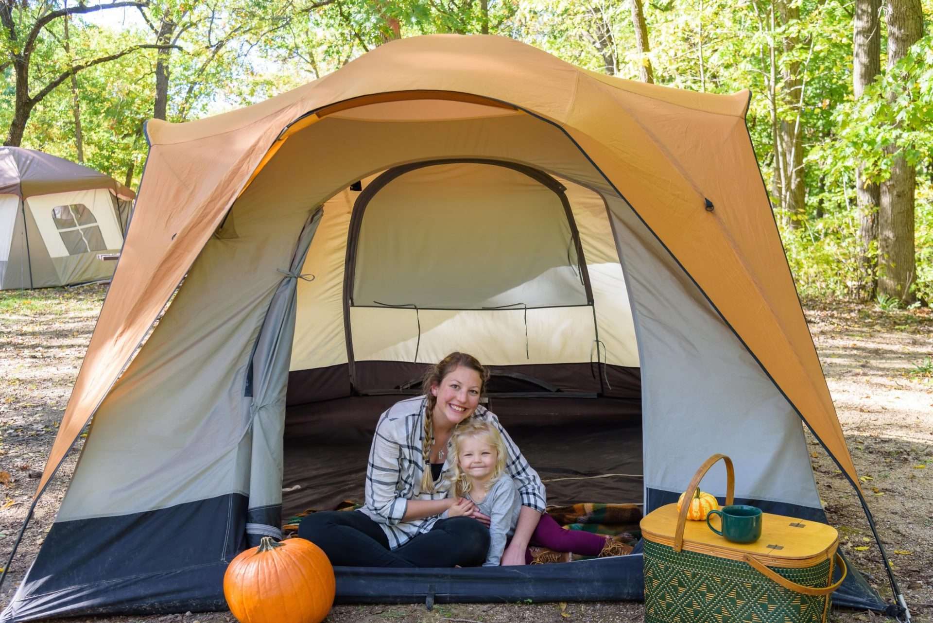 Mom and daughter sitting together inside tent while camping