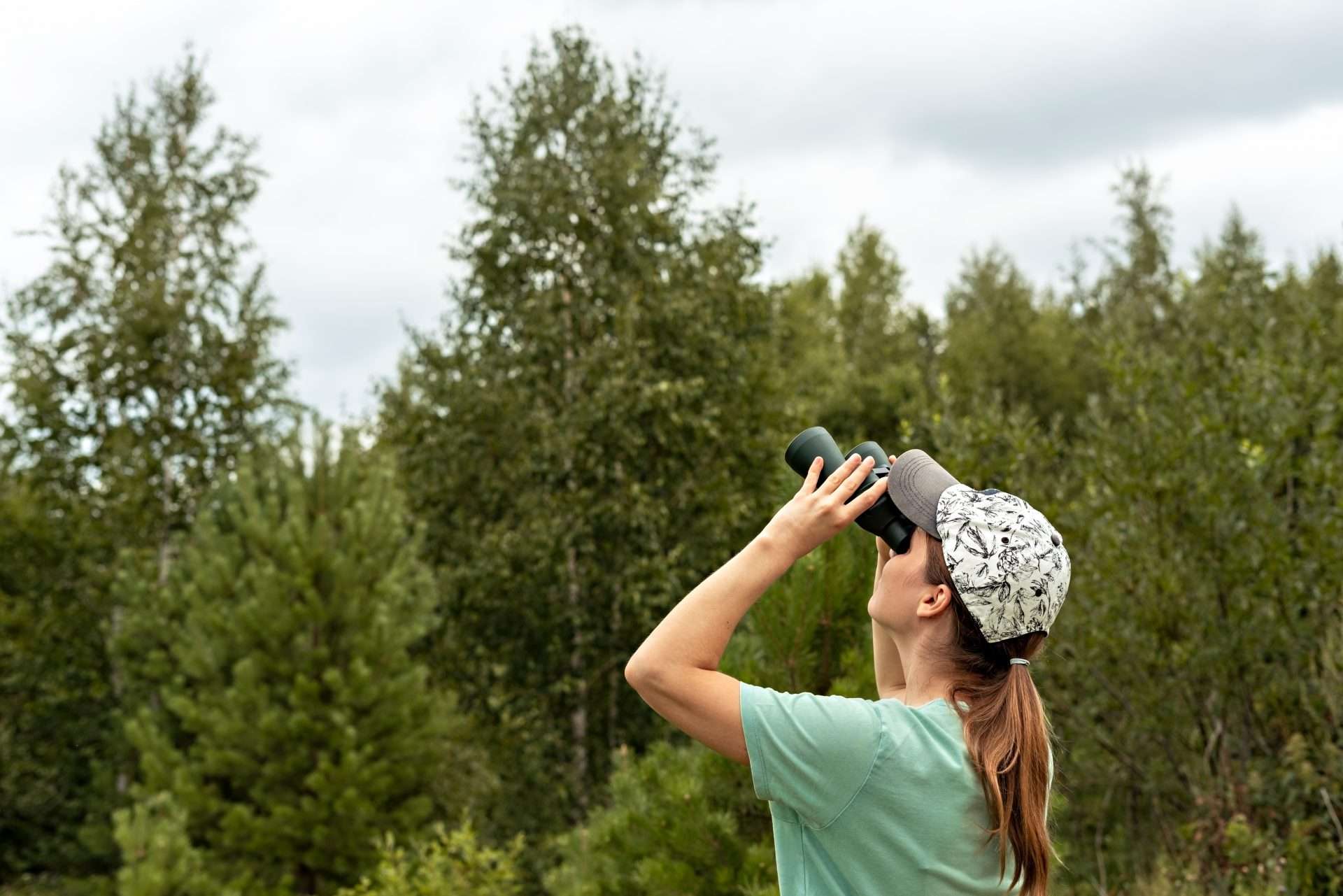 Woman using binoculars to bird watch while camping