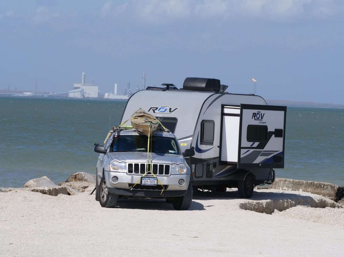 SUV and travel trailer parked on the beach with slide-outs open