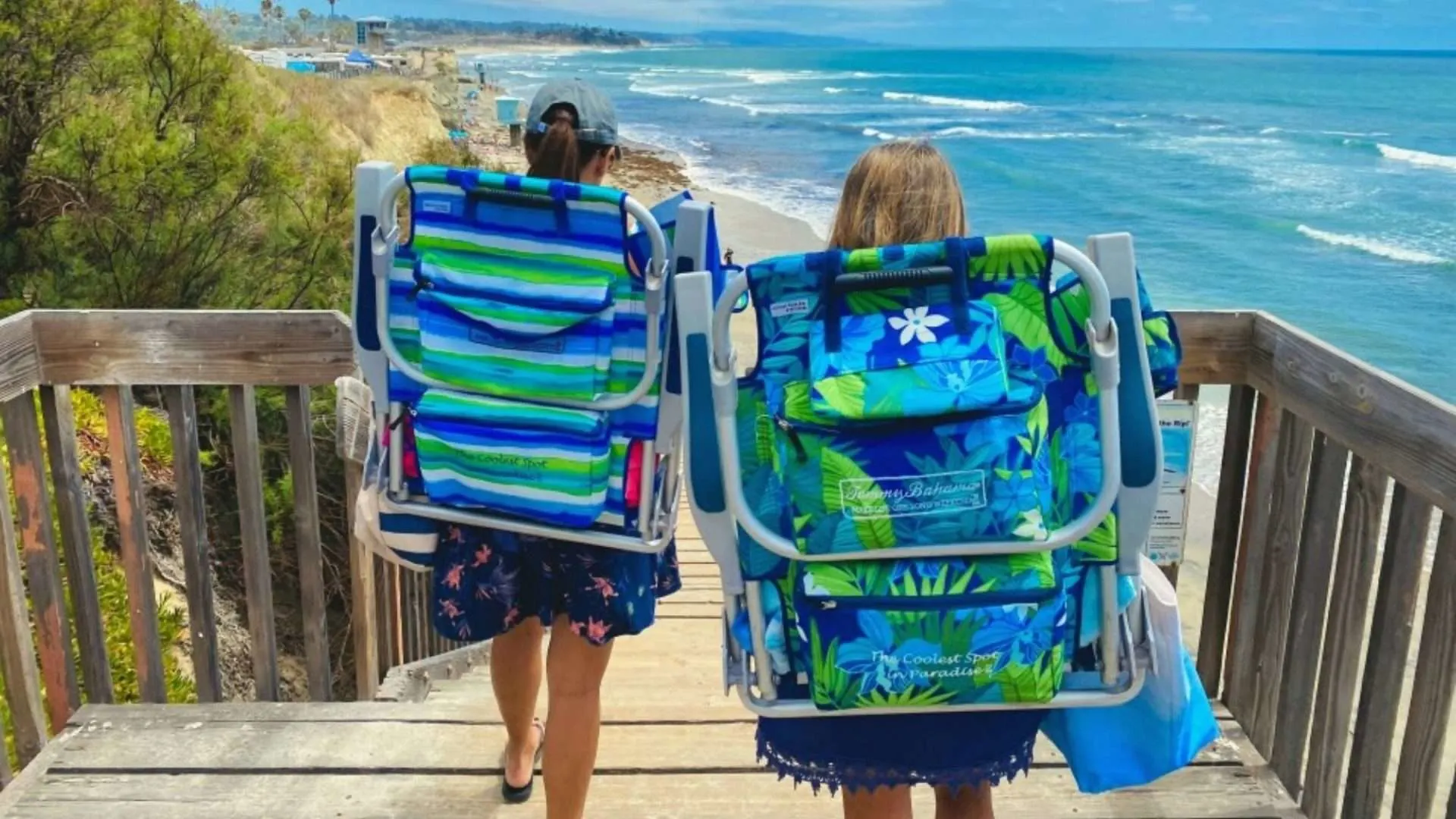 Two people carrying backpack beach chairs