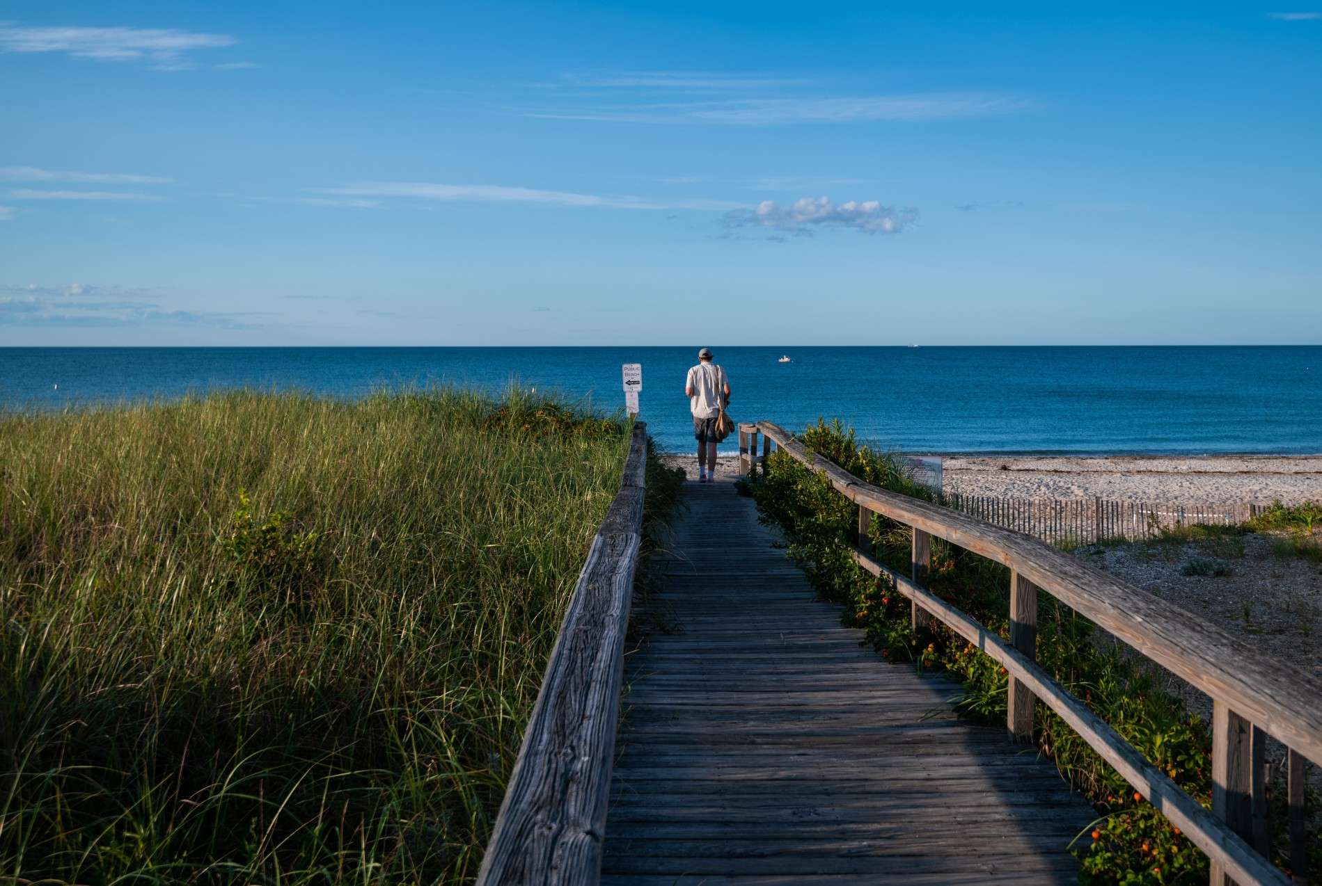 Man walking on boardwalk to the beach in Plymouth, Massachusetts. 