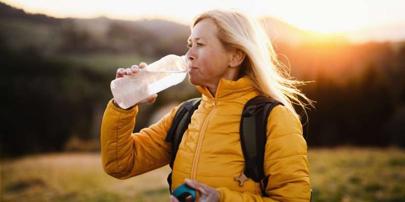 woman drinking purified water on hike