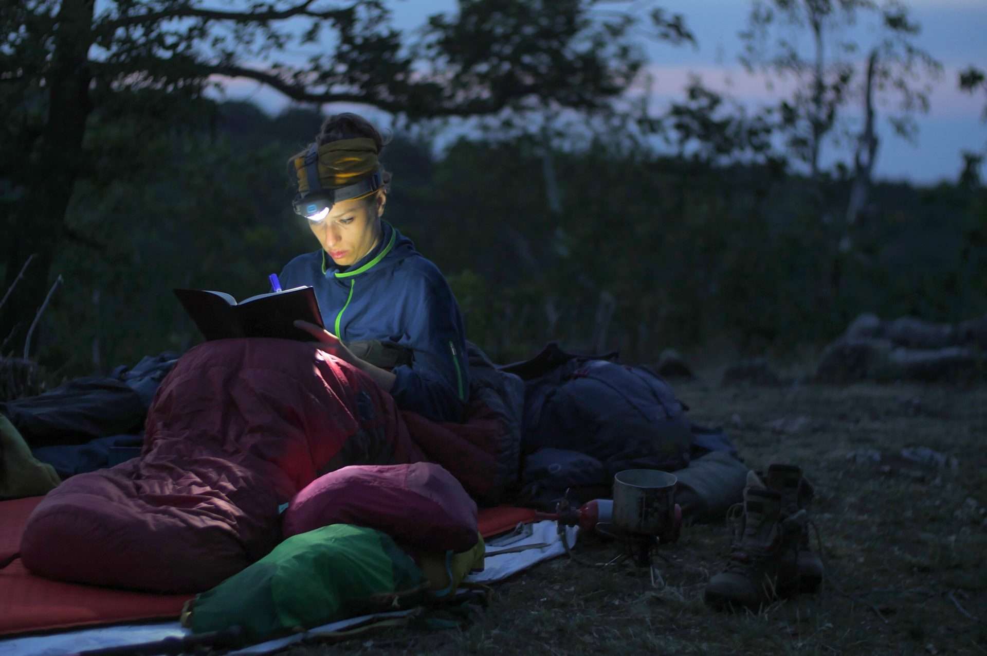 Woman using headlamp to read in sleeping bag