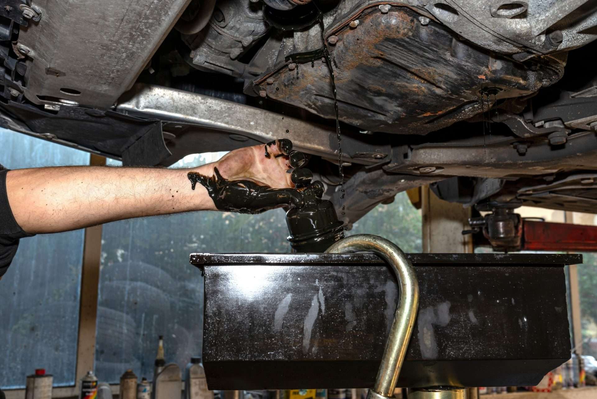 Mechanic fixing differential oil under car