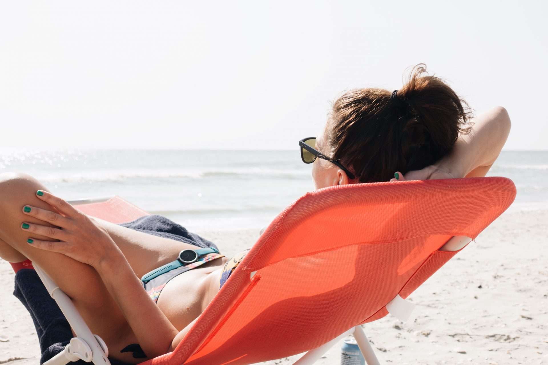 Woman relaxing on beach in red beach chair