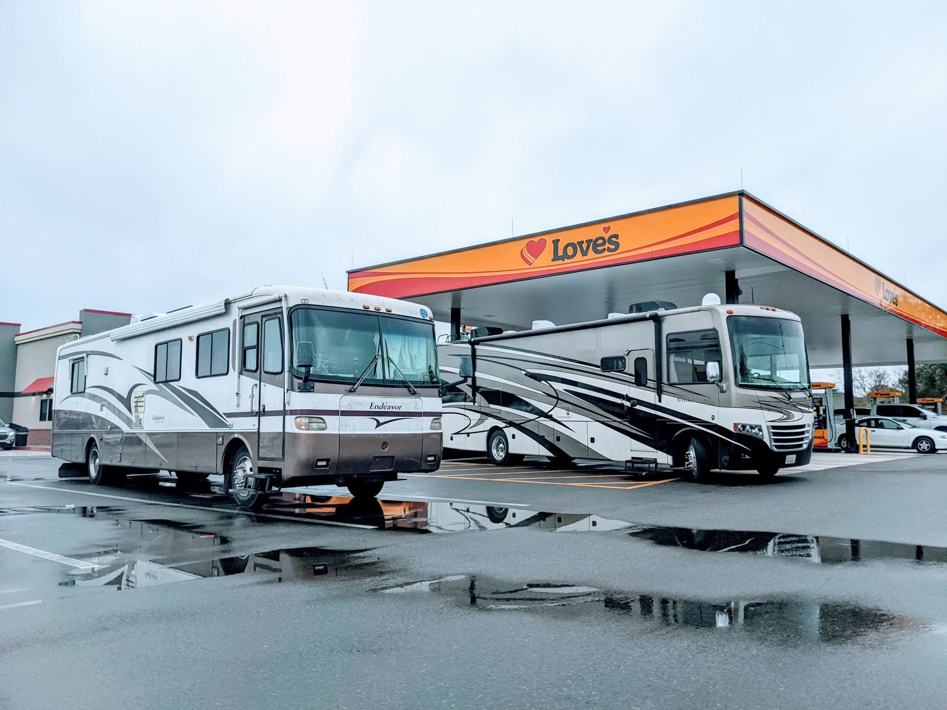 Two Class A motorhomes parked at Loves gas station fueling up with TSD Open Roads