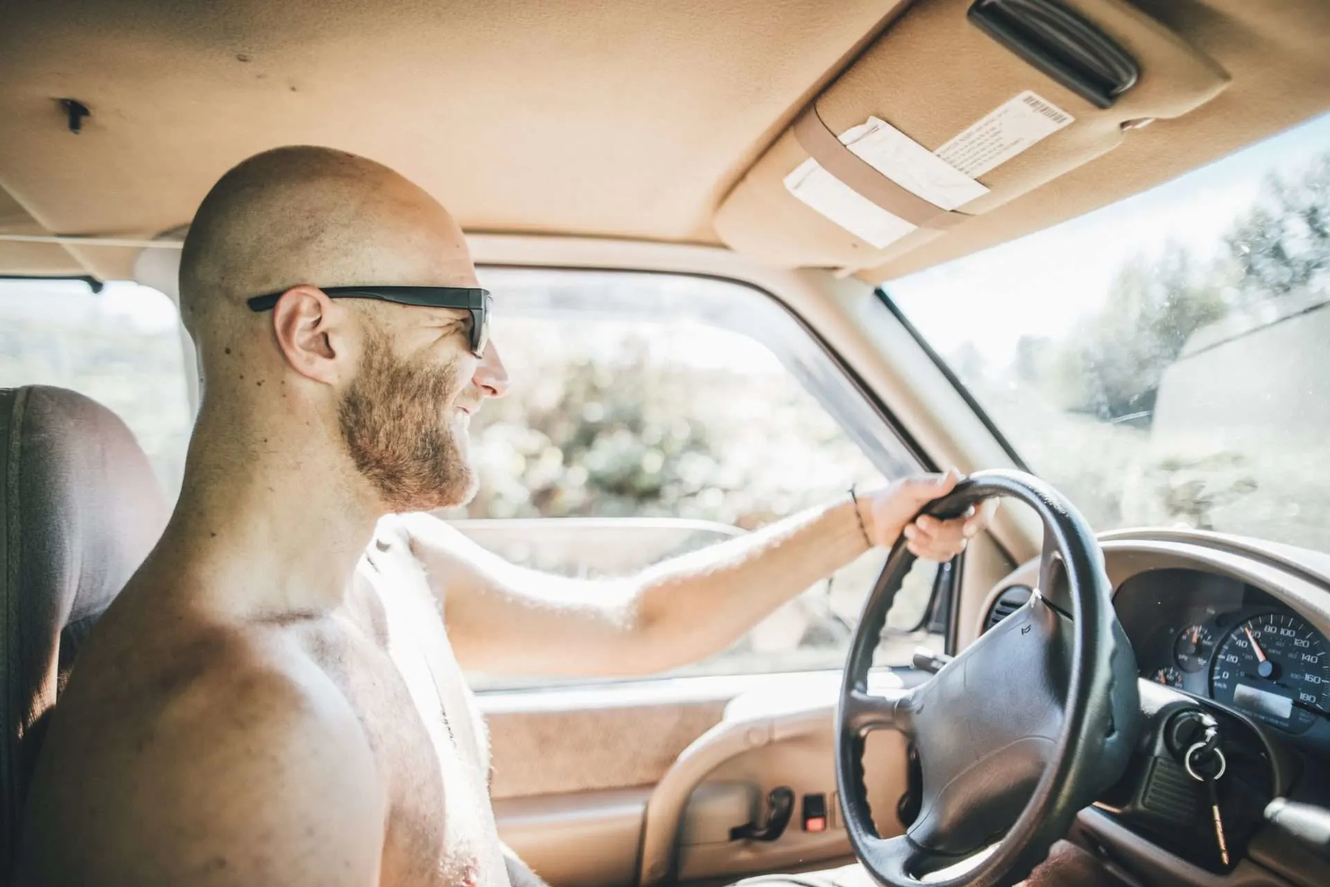 Man driving shirtless on road trip
