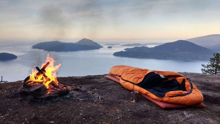 cowboy camping on mountain with sleeping bag and campfire