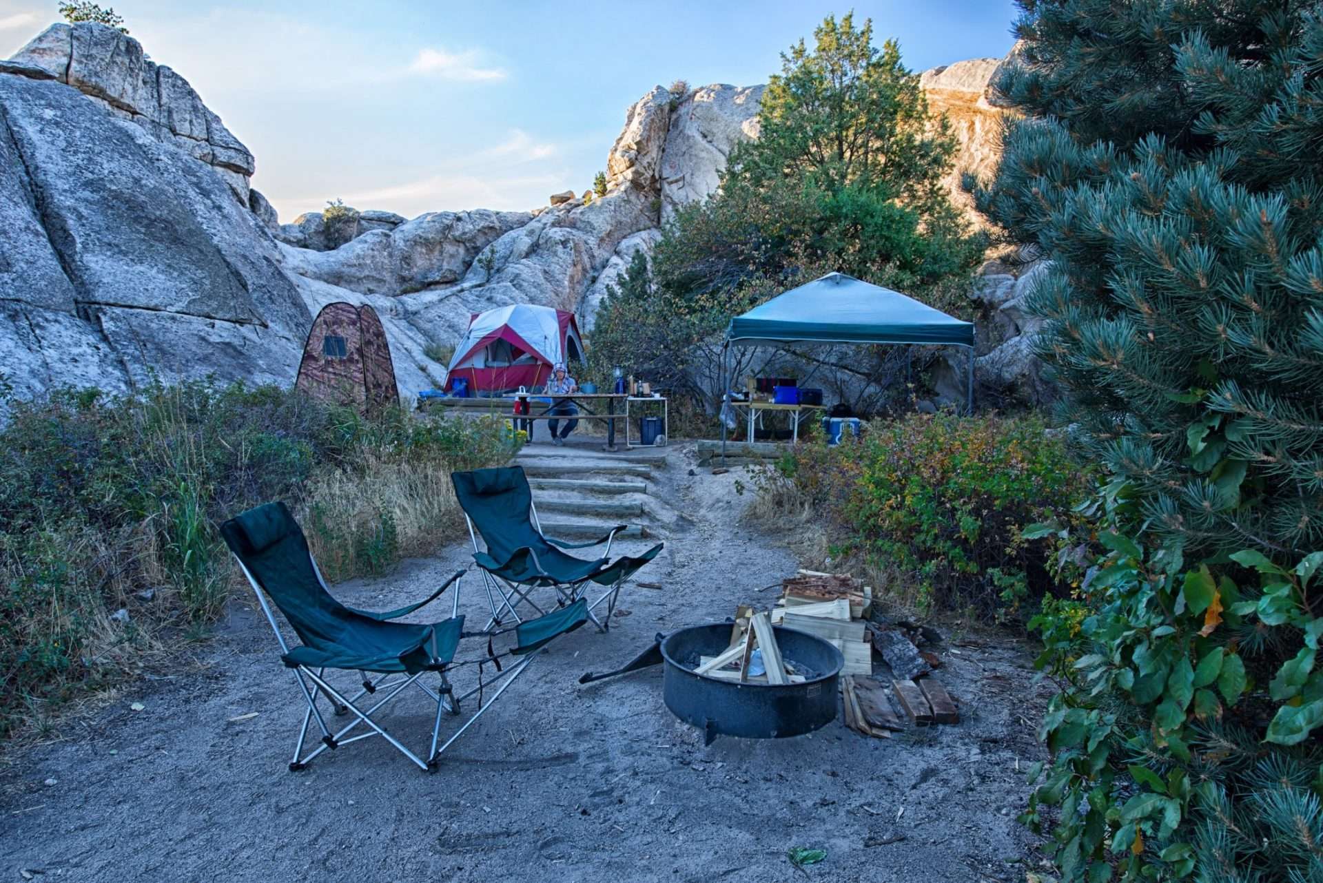 Campground set up with tent, fire pit, and two rocking camp chairs
