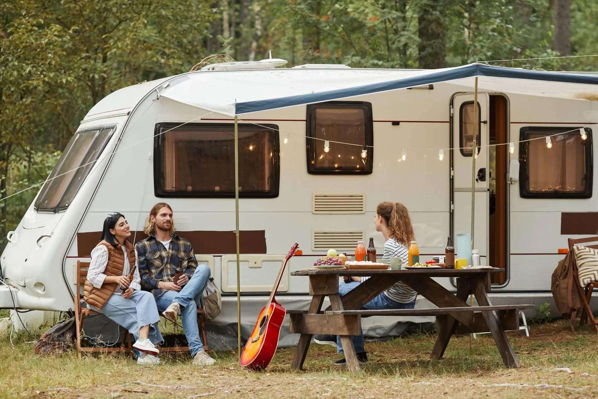 Friends enjoying a picnic in front of RV at campground