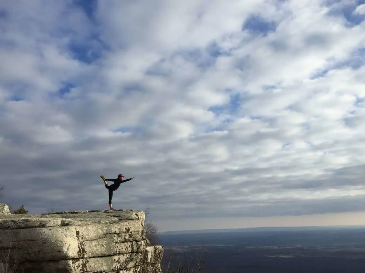 Woman doing yoga pose at the top of a cliff in the Catskills
