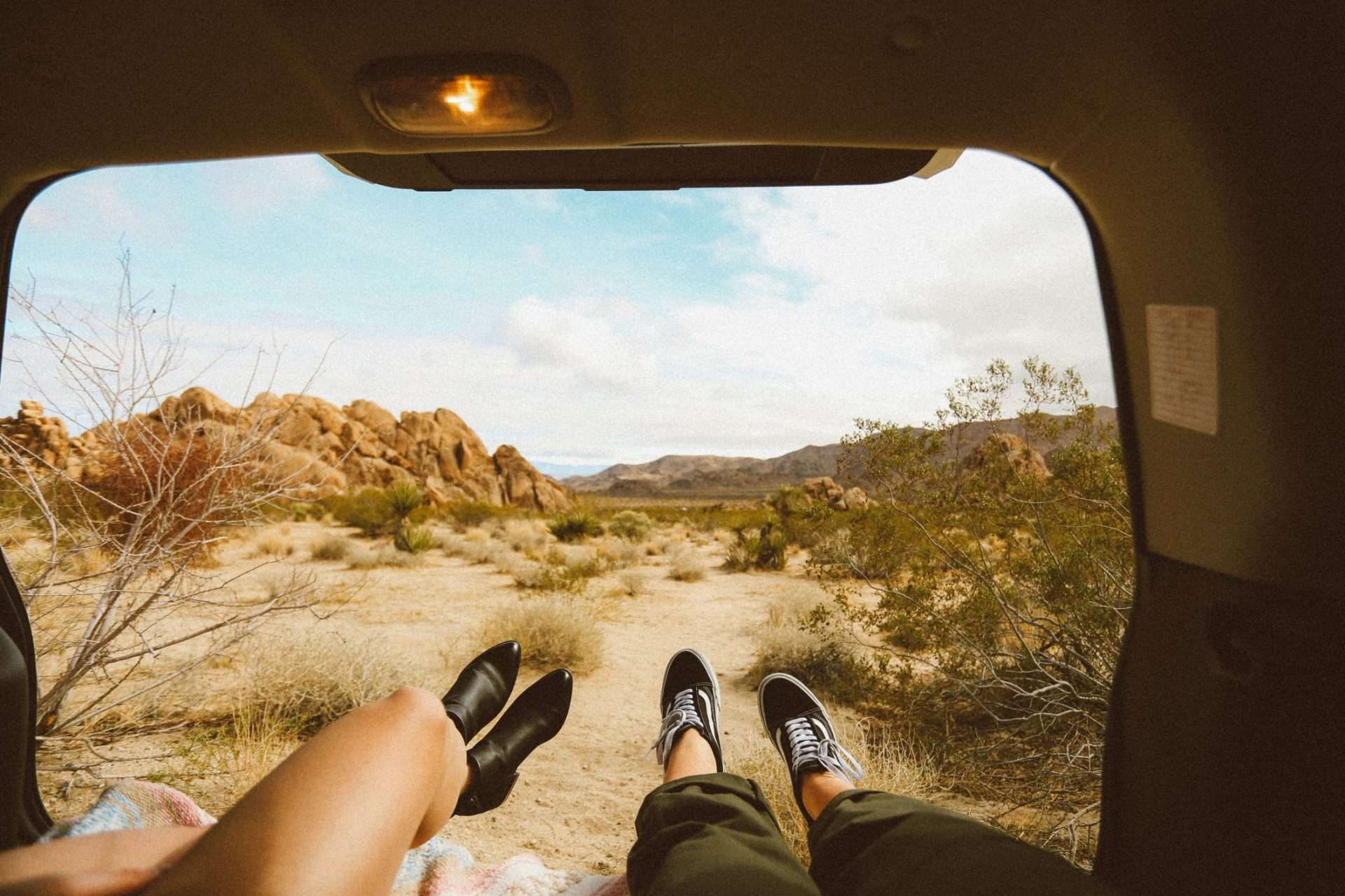 Couple sitting in back of camper van looking out into Joshua Tree
