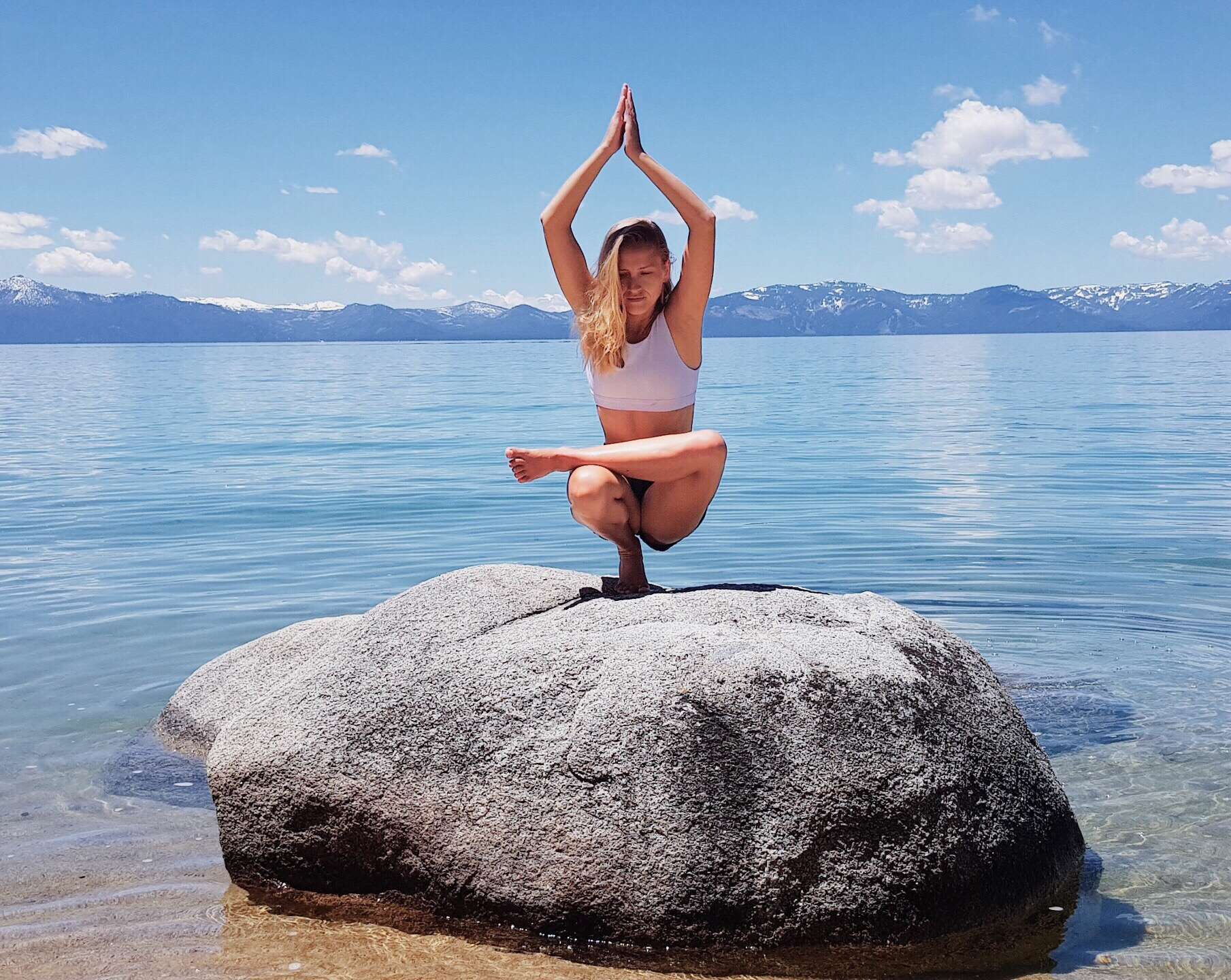 Woman doing yoga on a rock in front of Lake Tahoe