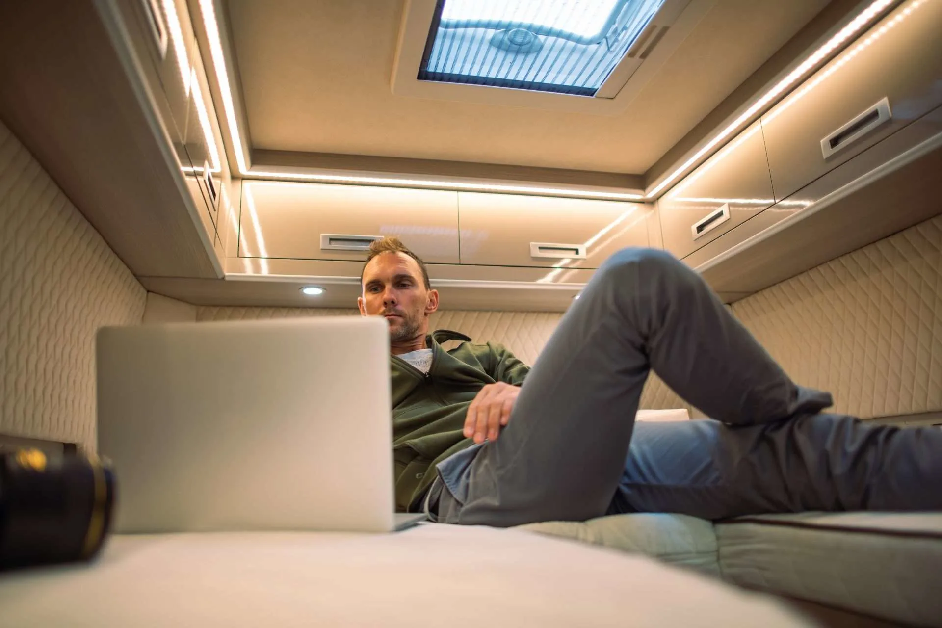 Caucasian Men Laying in His RV Camper Van Bed in Front of His Laptop Computer and Watching His Favourite Online Movie Service.