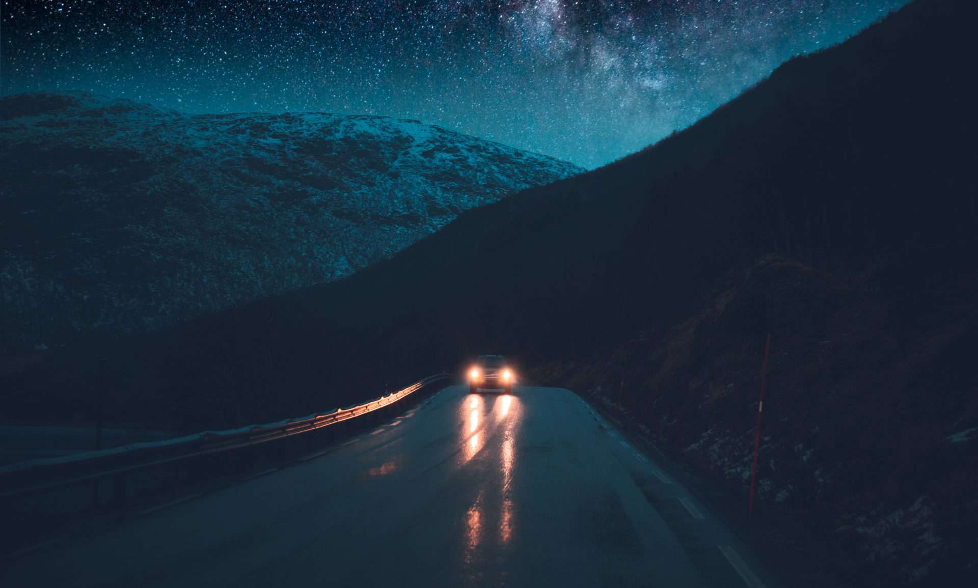 Car driving on wet winding road at night