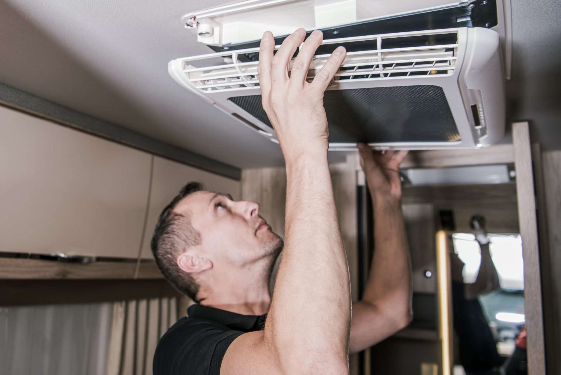 Man installing new air conditioner in renovated RV.