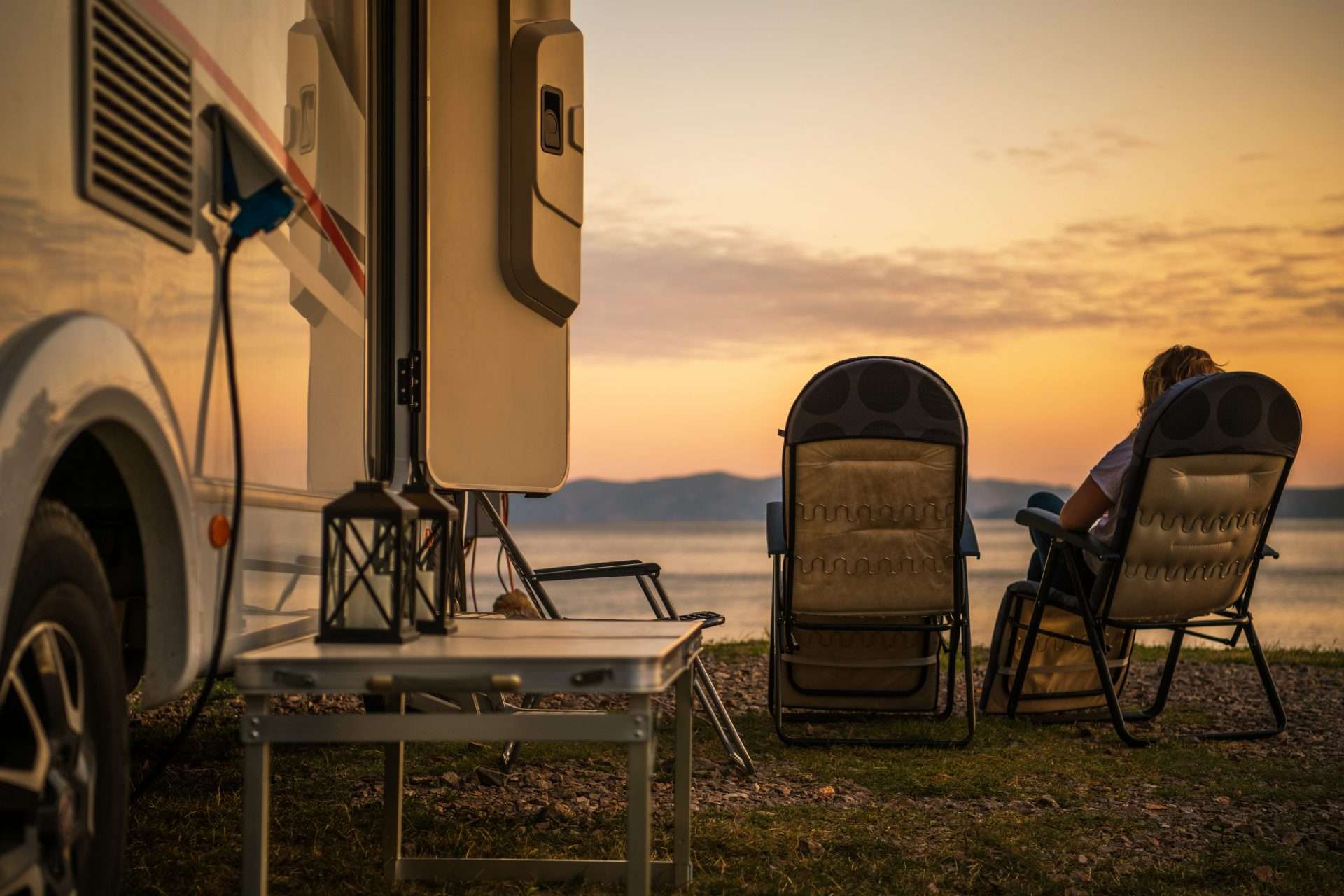 Two people sitting in comfortable chairs looking at sunset in RV campground