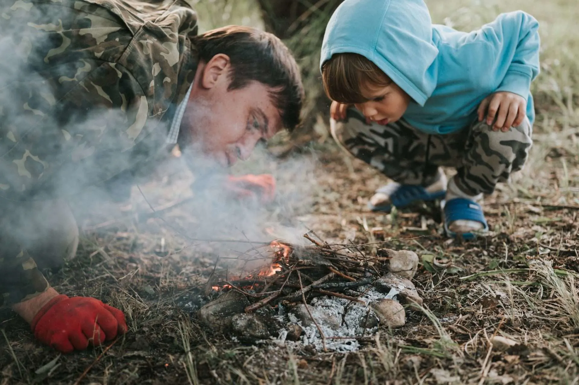 Father and son building a fire together while survival camping