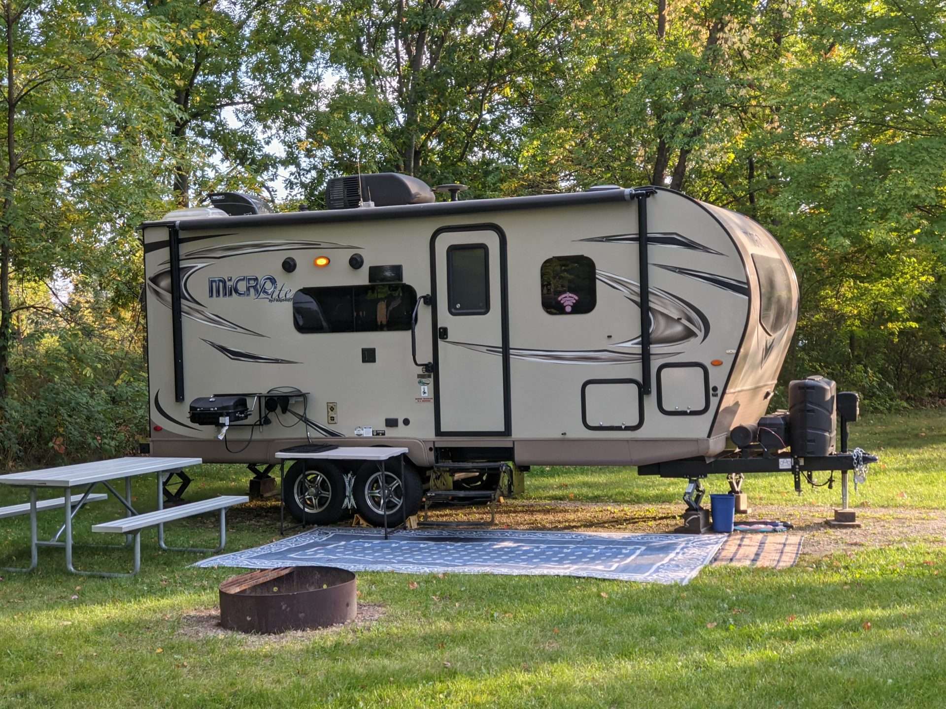 RV with outdoor rug next to it.