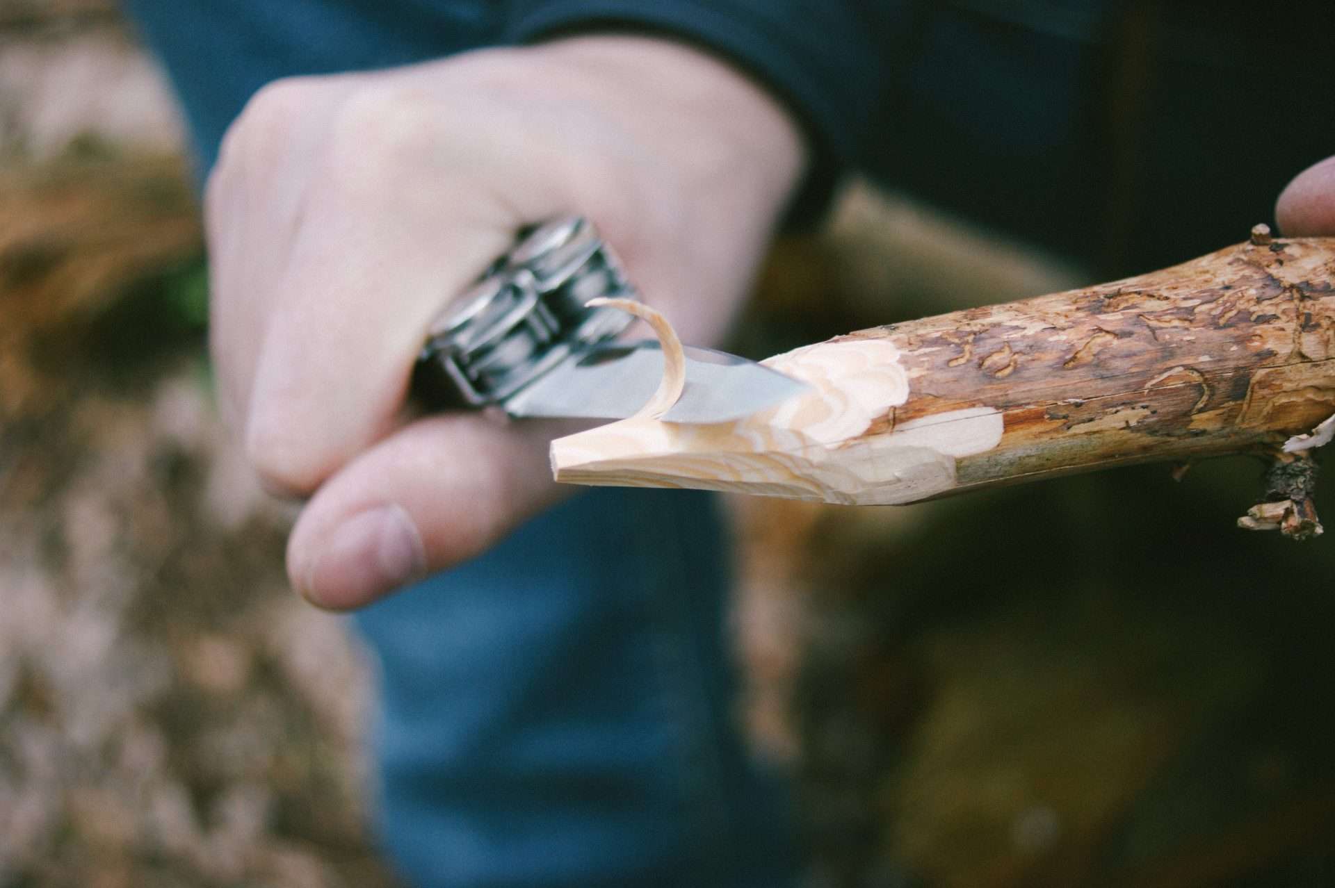 Man whittling arrow with a survival knife