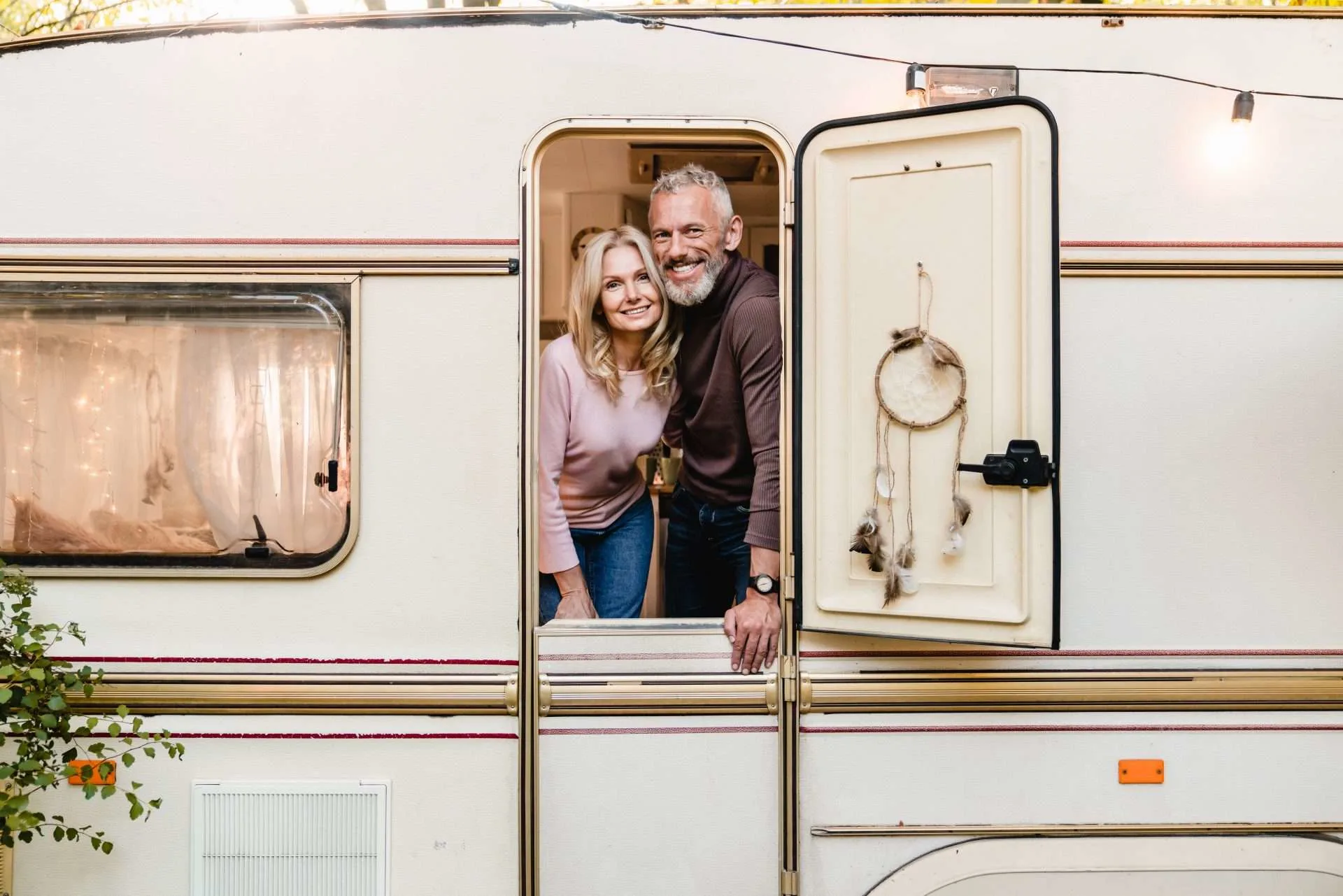 Older couple smiling in doorway of RV while moochdocking