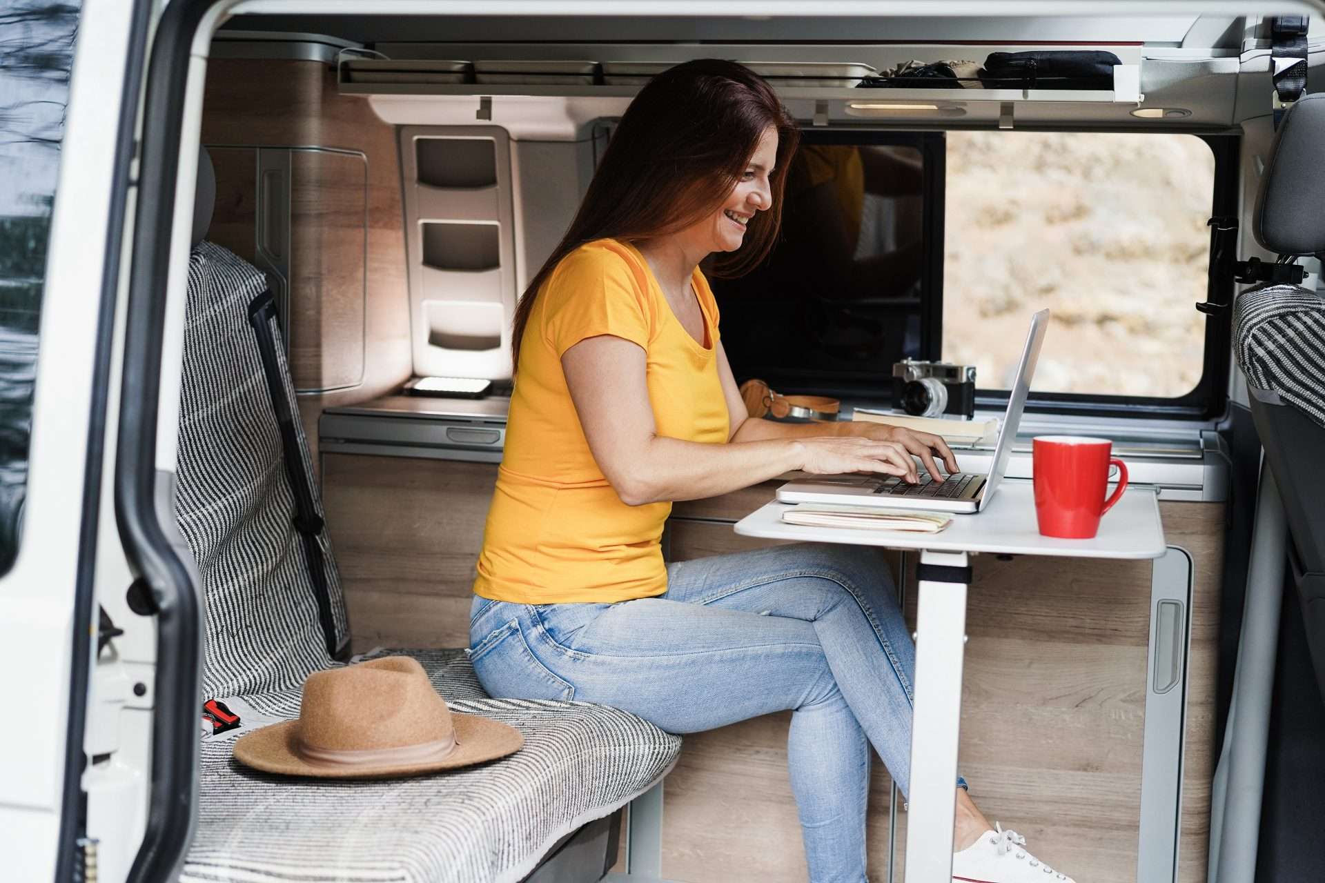 Woman using laptop inside camper van