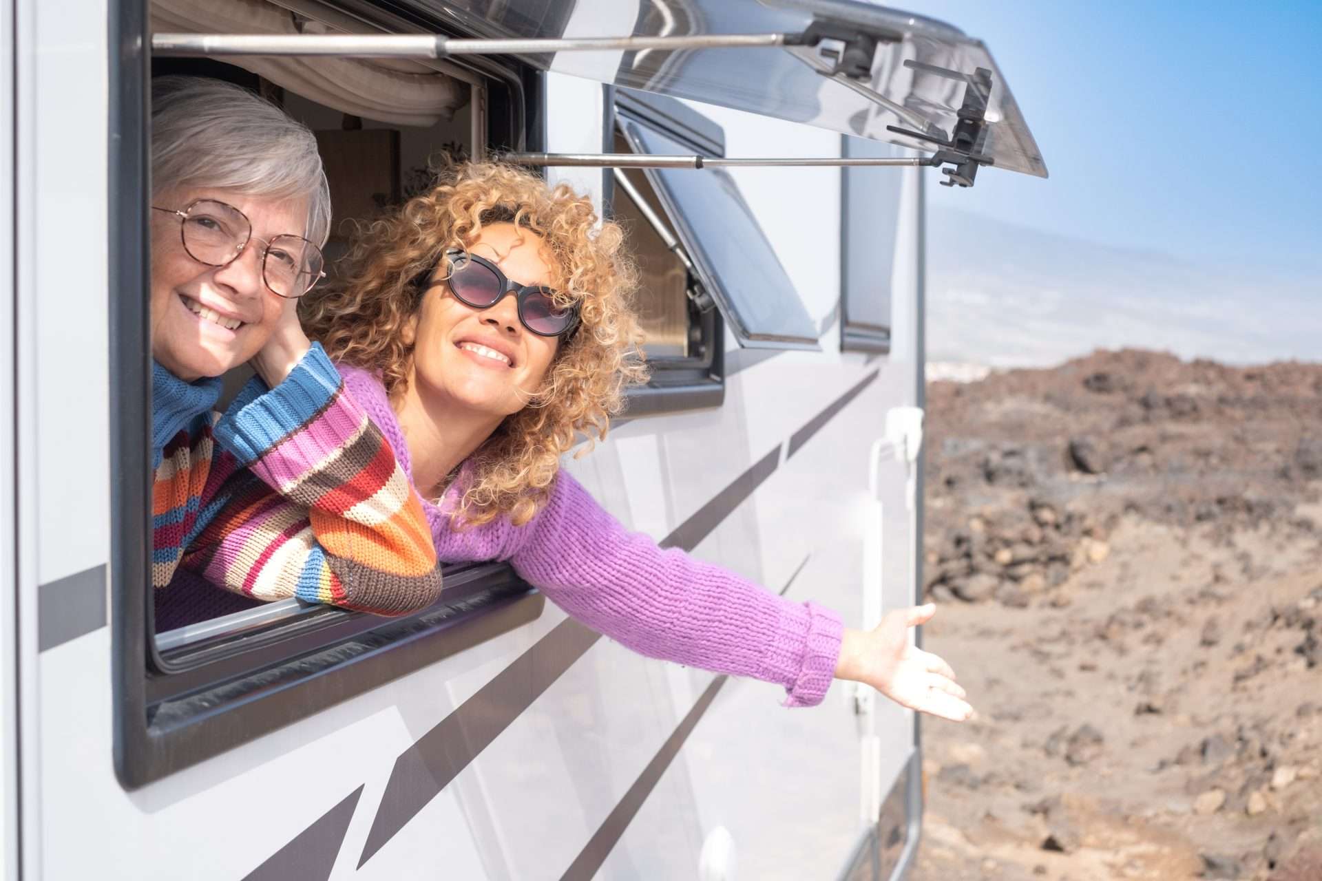 Two women leaning out RV window happily