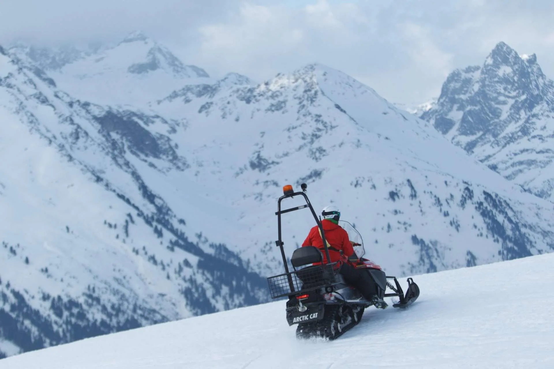 Man driving snow mobile ORV on snowy mountain.