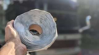 holding up a roll of butyl tape in front of an RV
