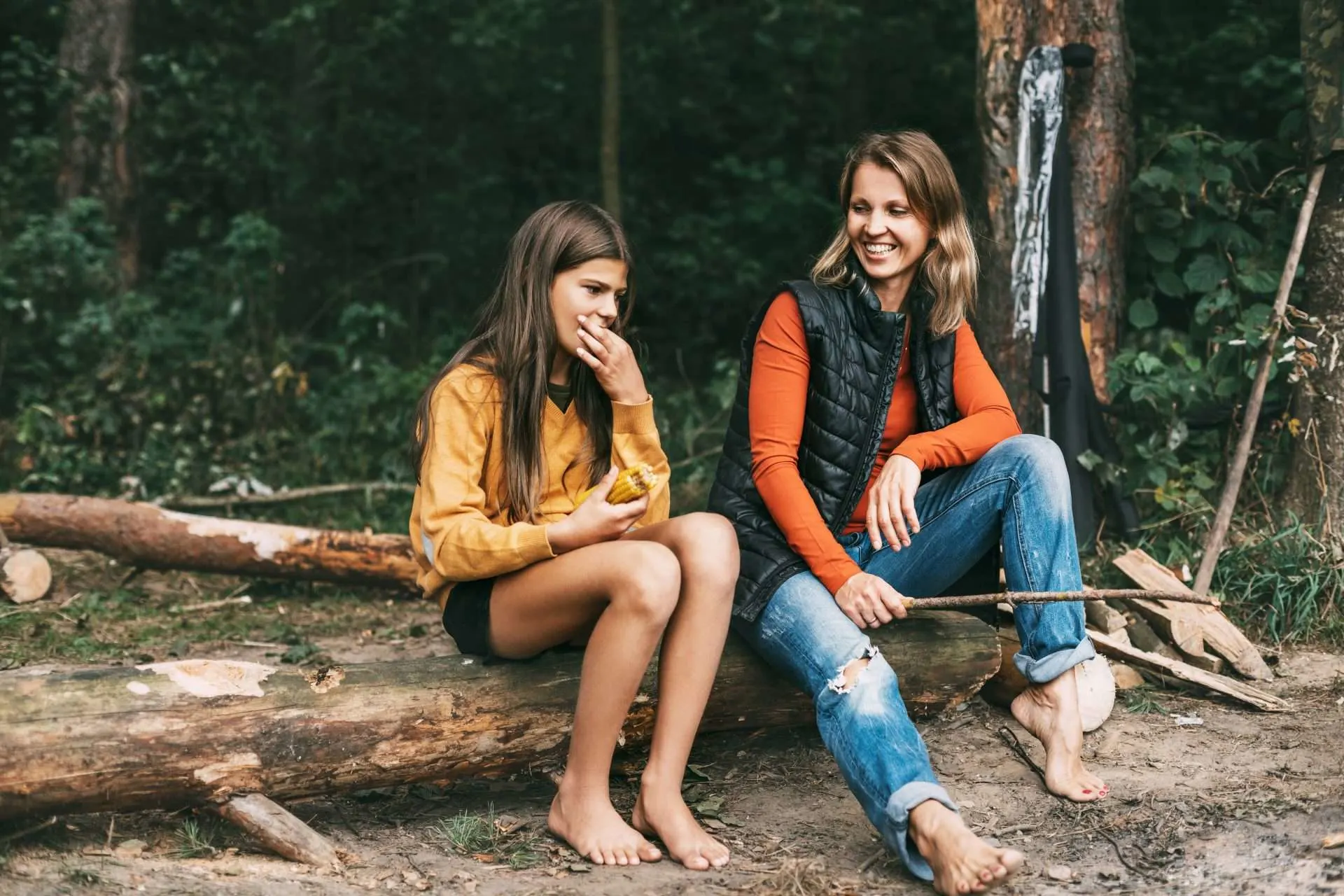 Mom and daughter eating food together on camping trip while learning survival skills