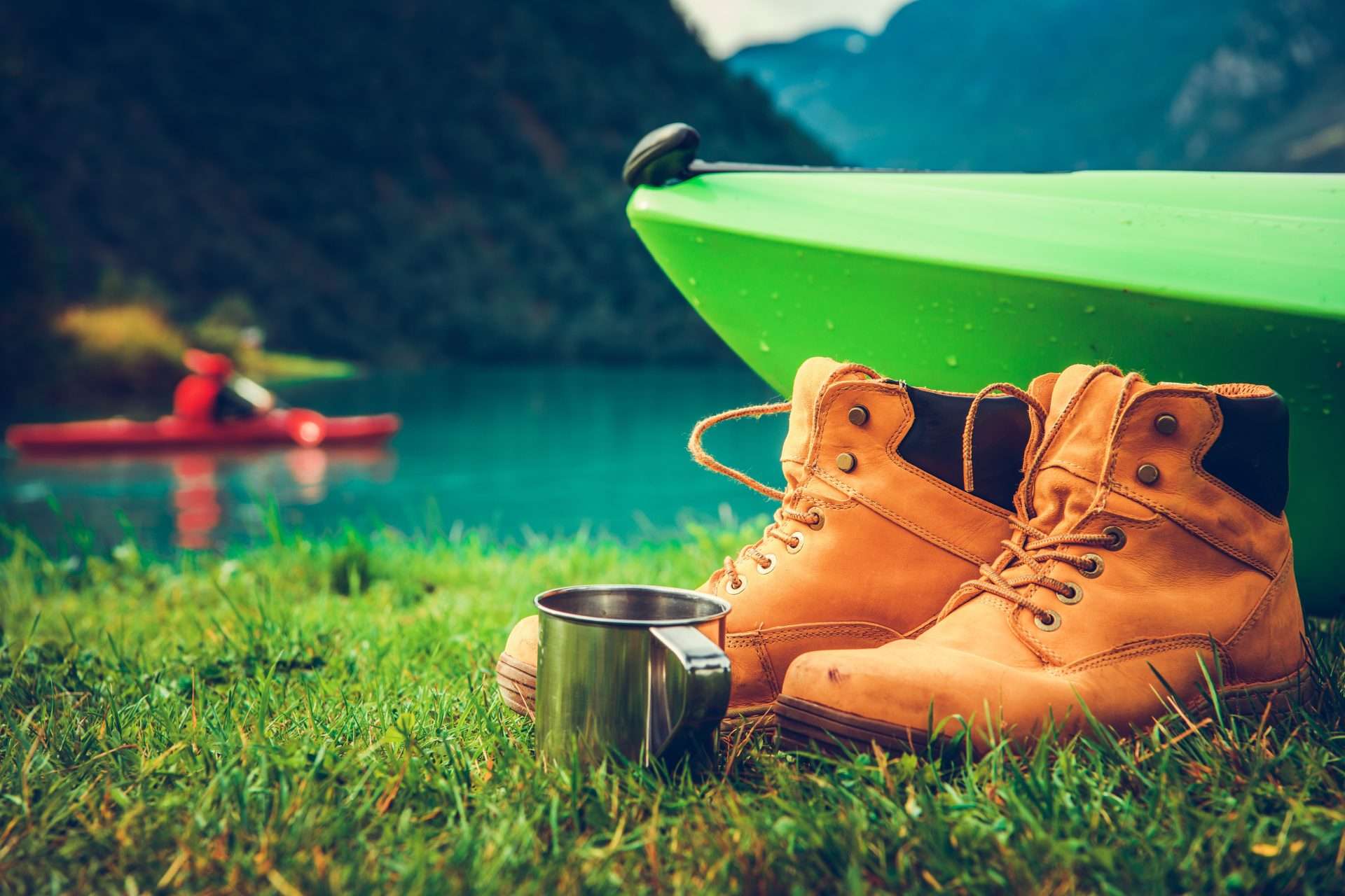 Close up of kayak along water with hiking boots and camping mug