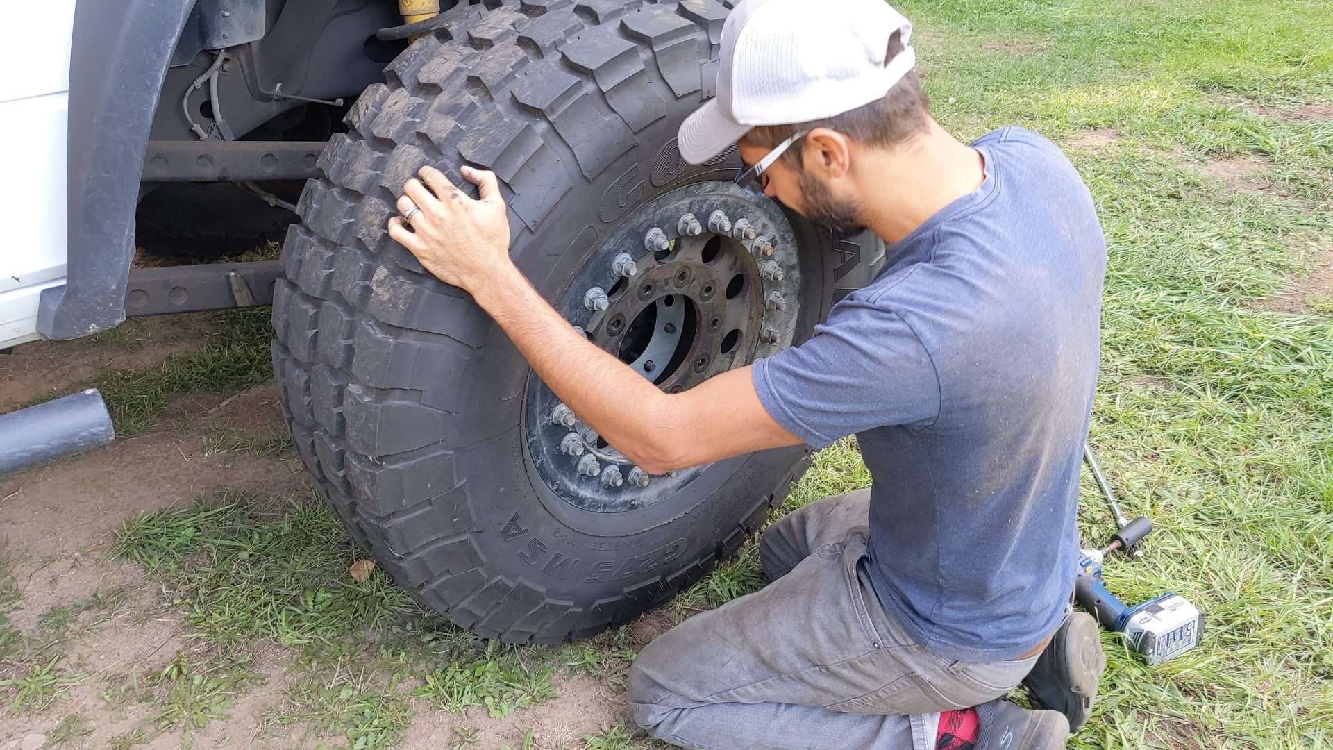 Tom rotating tires and installing wheel balancers on their overland truck camper