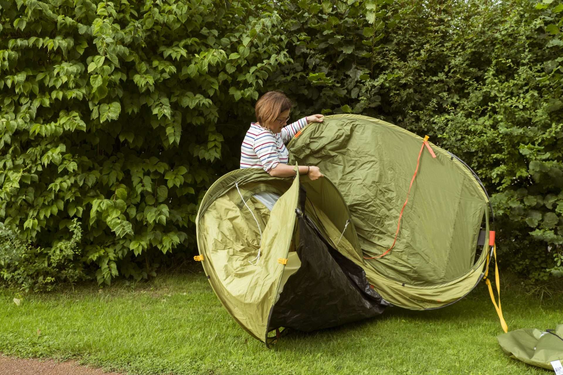Woman opening green pop-up tent