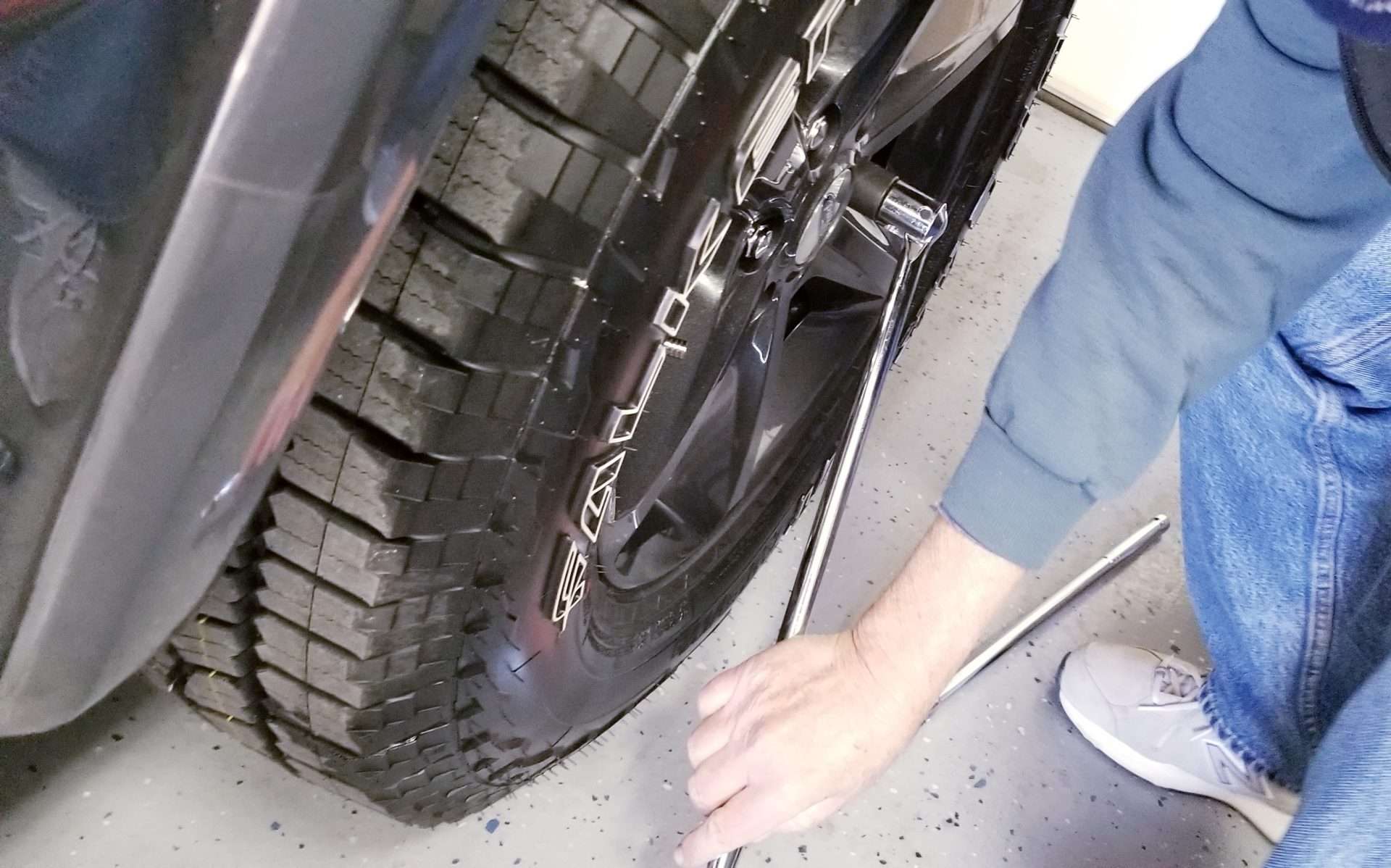 Person removing lug nuts from tire.