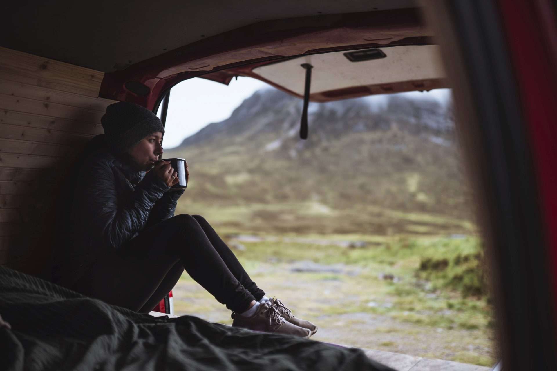 Woman drinking coffee while camping in camper van