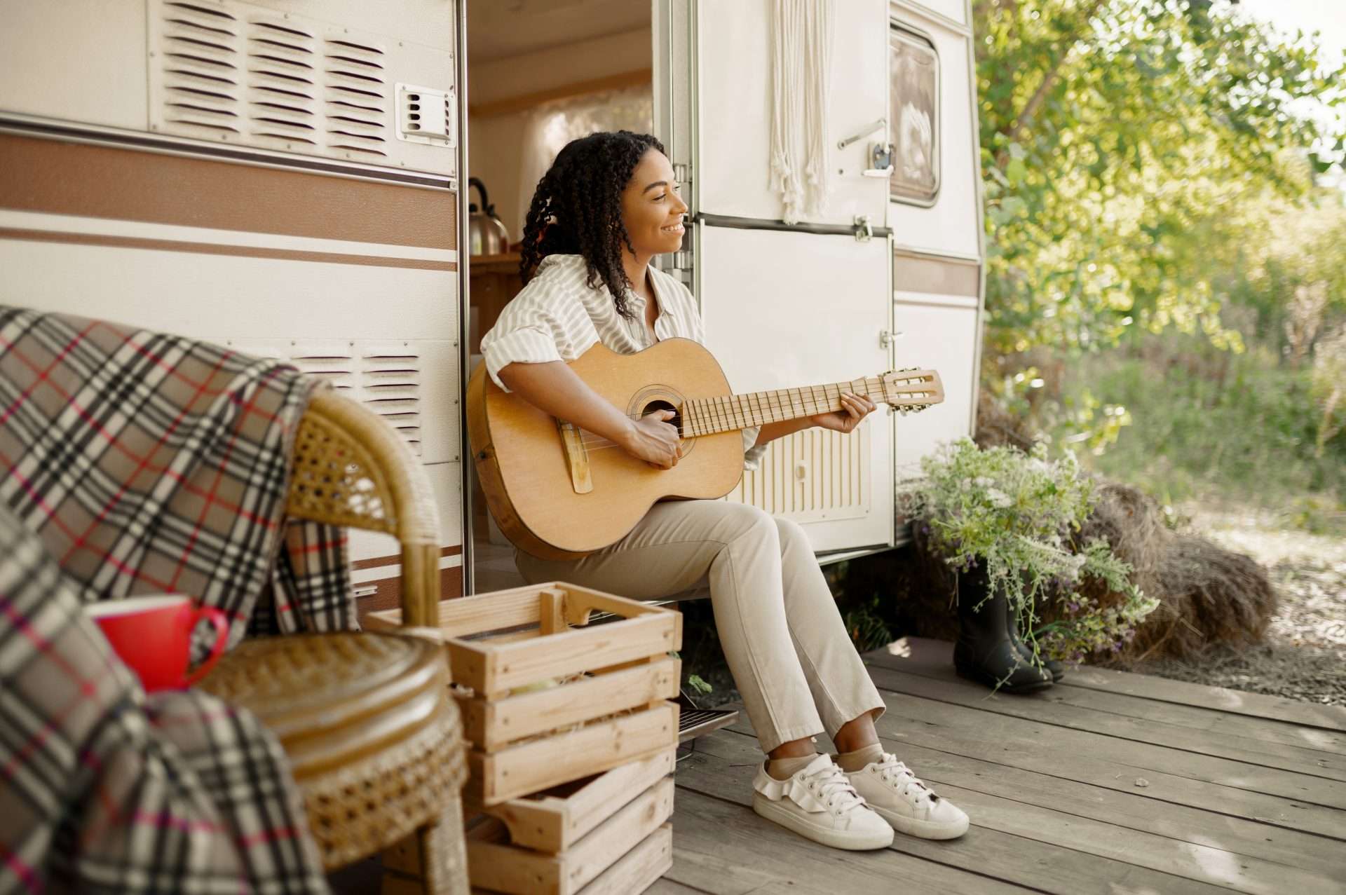 Woman playing guitar while sitting on RV porch