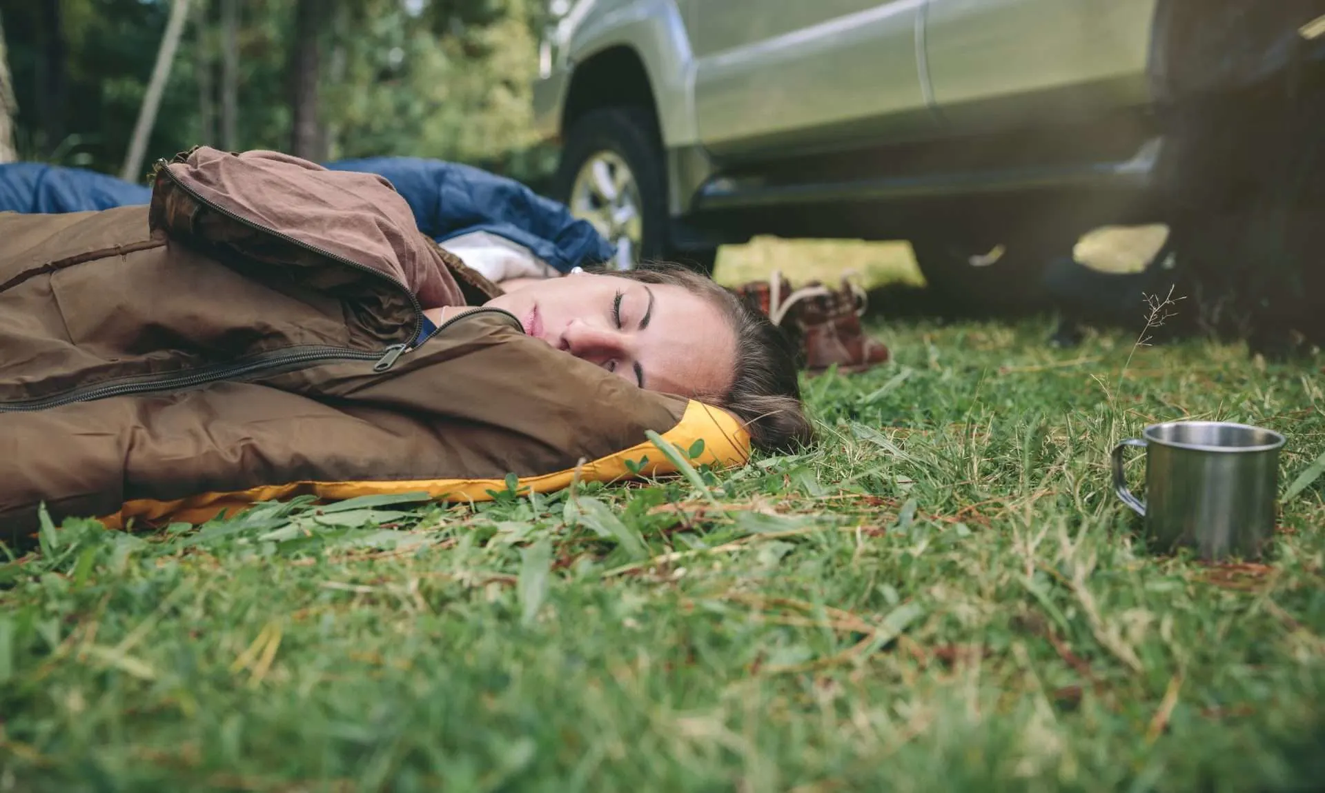 Woman sleeping in sleeping bag without sleeping pad while camping