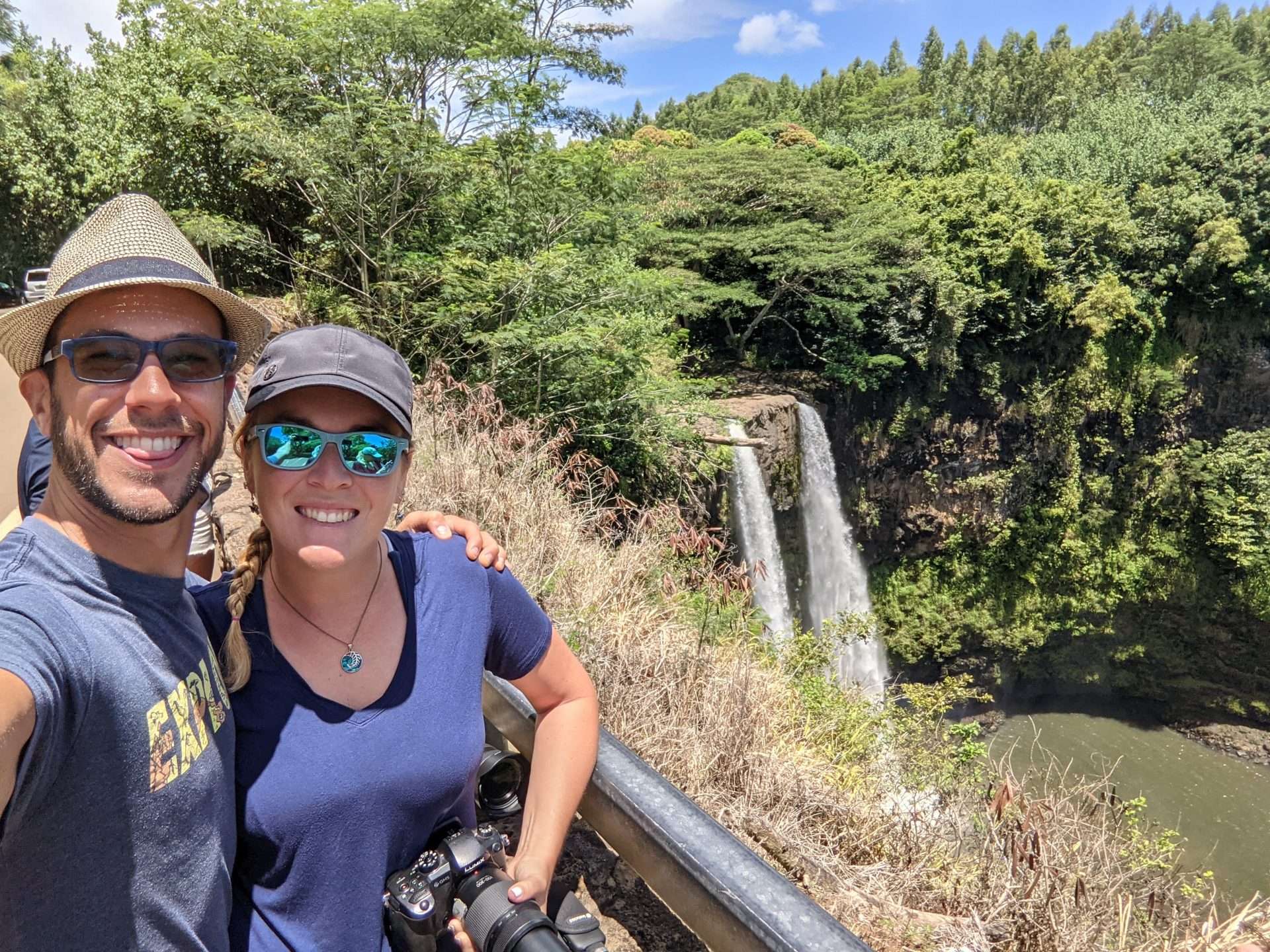 Tom and Caitlin from Mortons on the Move hiking by waterfall in Hawaii