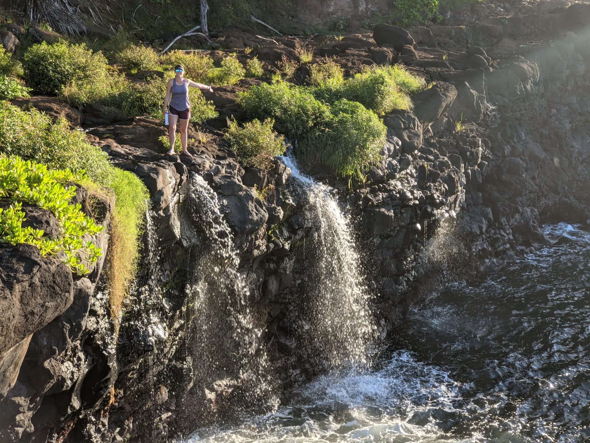 Caitlin from Mortons on the Move at the top of a waterfall while hiking in Hawaii