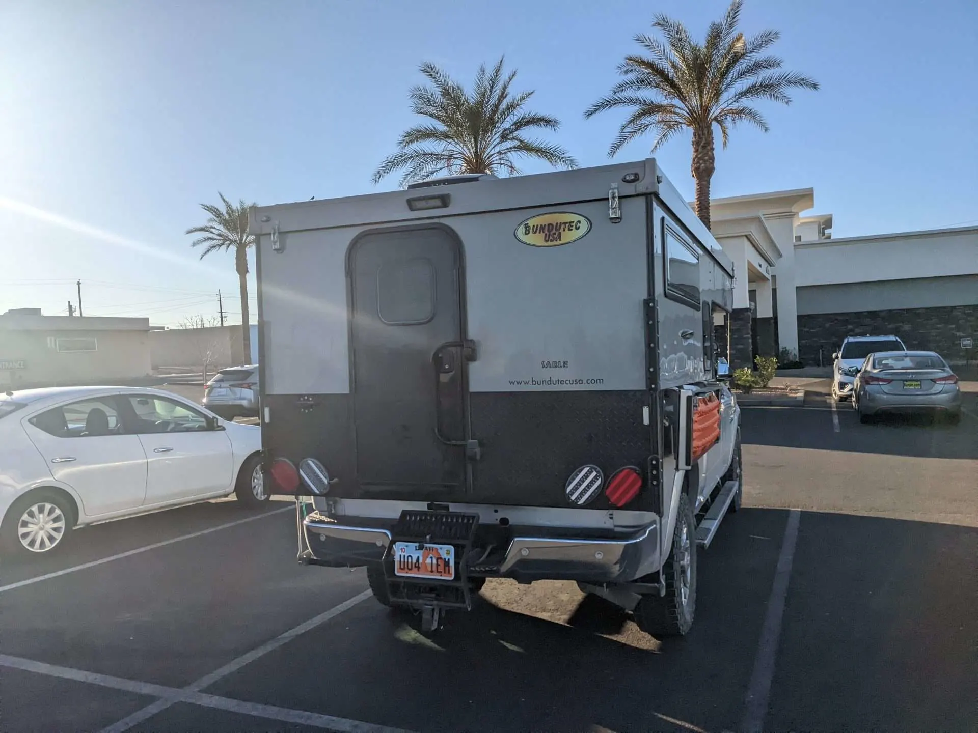 Truck camper parked in parking lot by palm trees while stealth camping in Florida