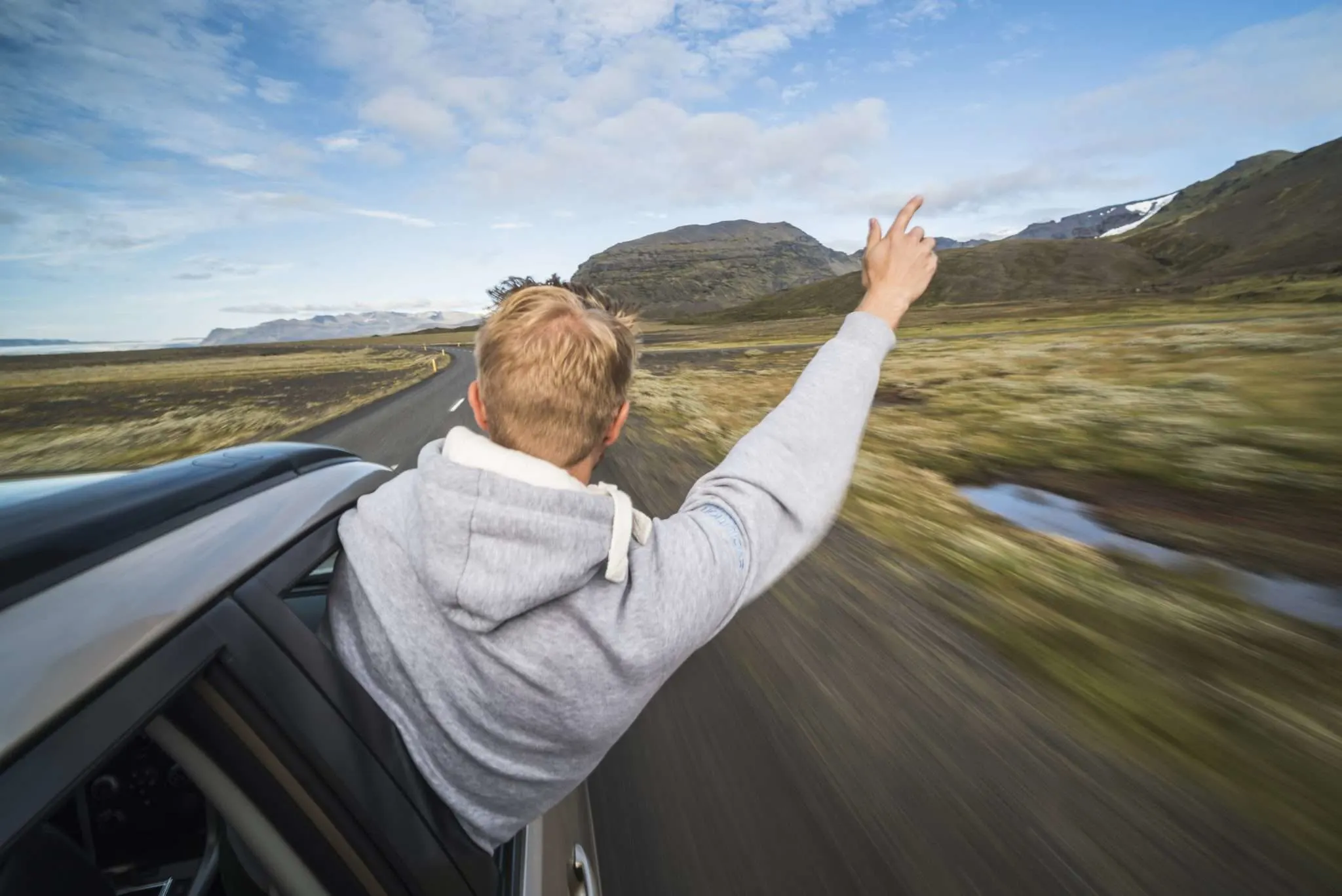 man hanging out of vehicle in iceland