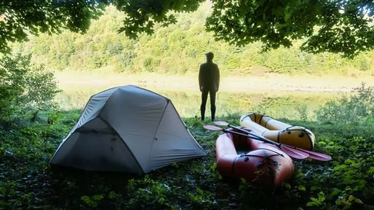Man near tent and kayaks while camping