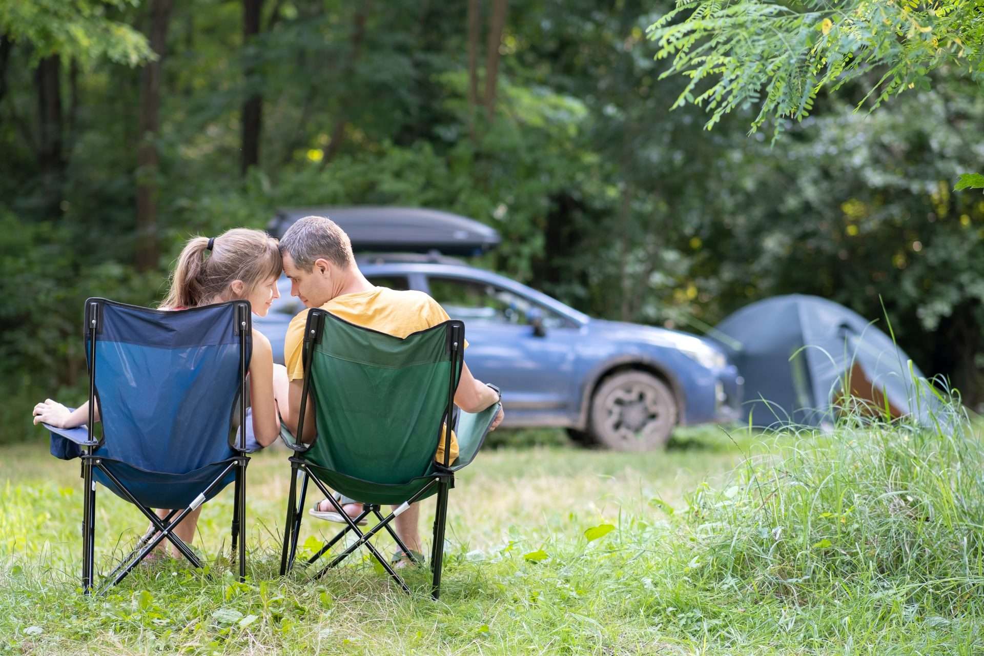 Couple sitting in front of Prius at a campsite