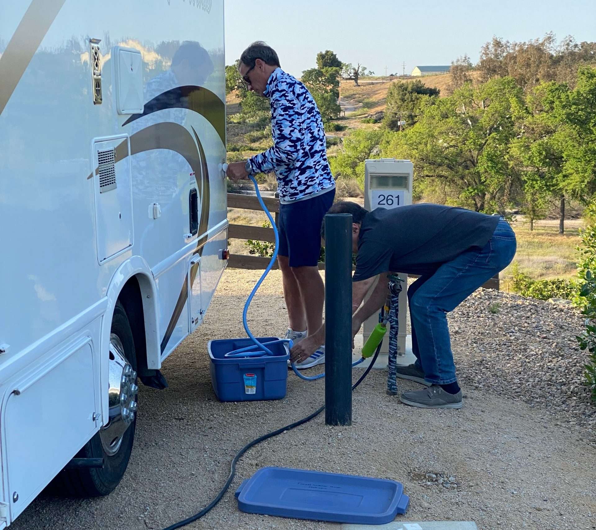 Couple hooking up RV to water system to refill water tank