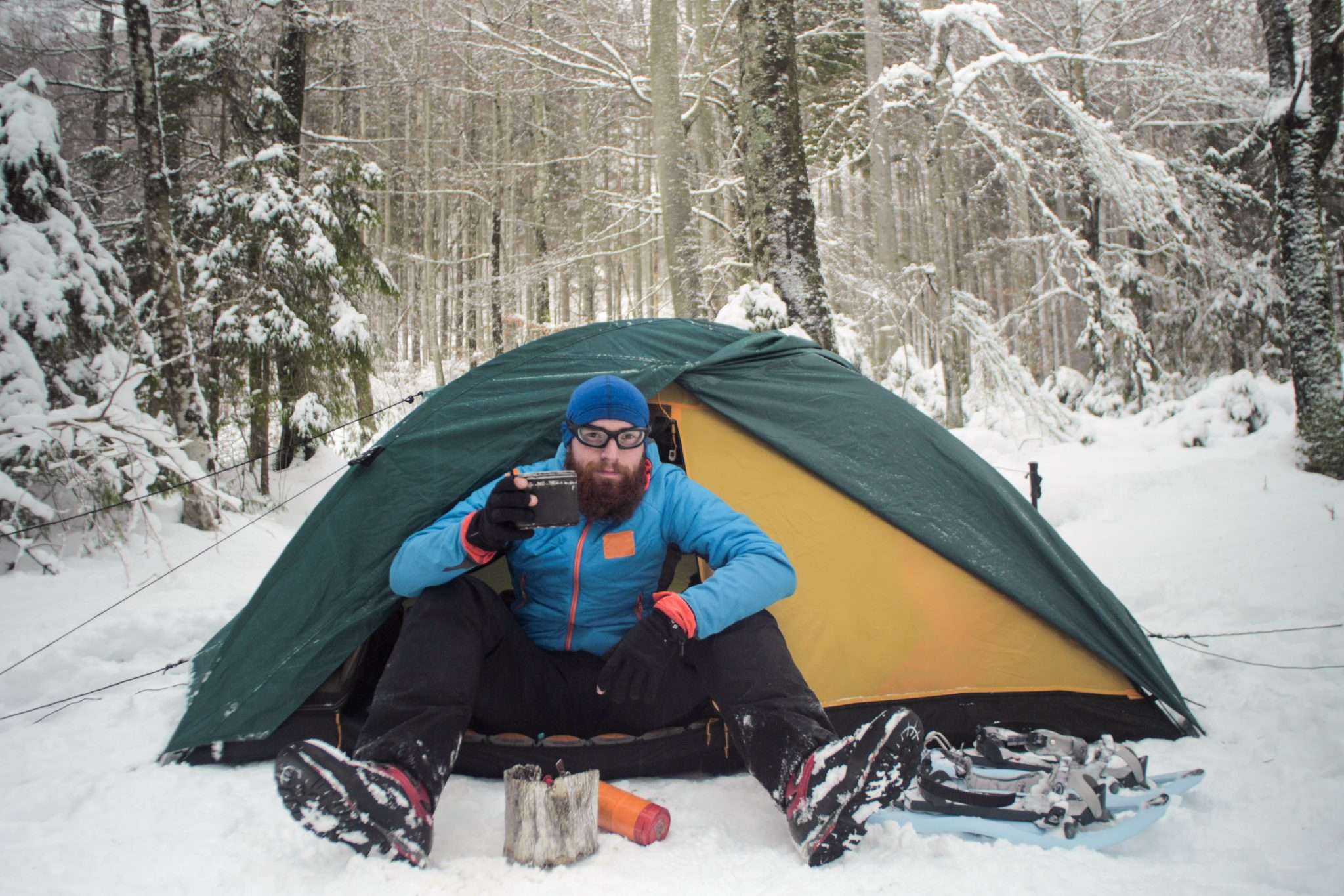 Man cold weather camping in snow with tent heater