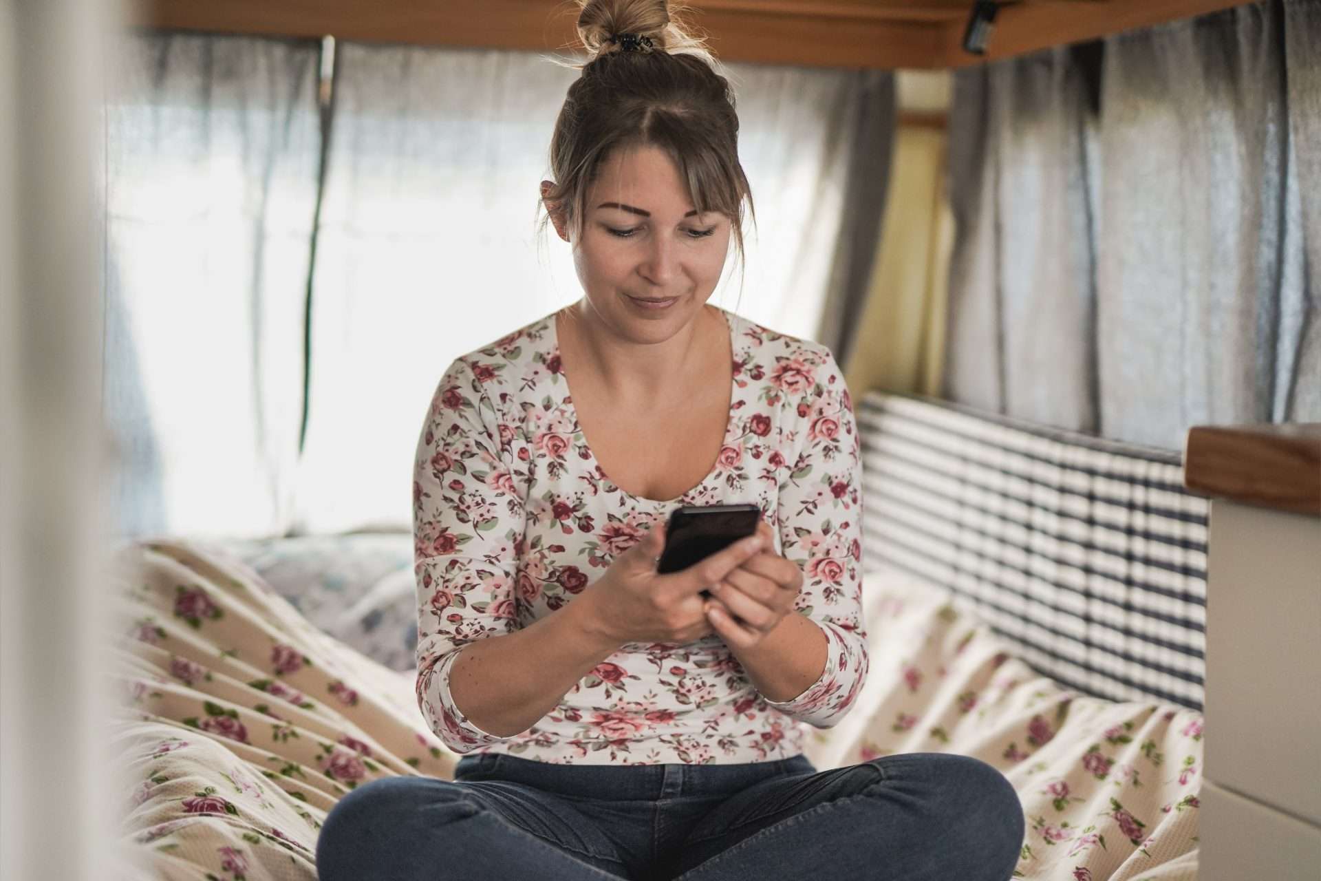 Woman using Campendium phone app in RV